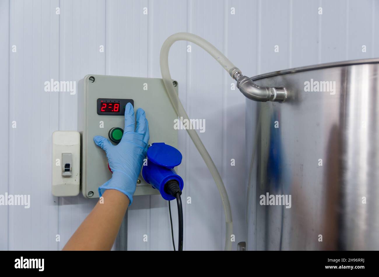 Frau, die in der Industrie arbeitet und den Tankthermostat justiert Stockfoto