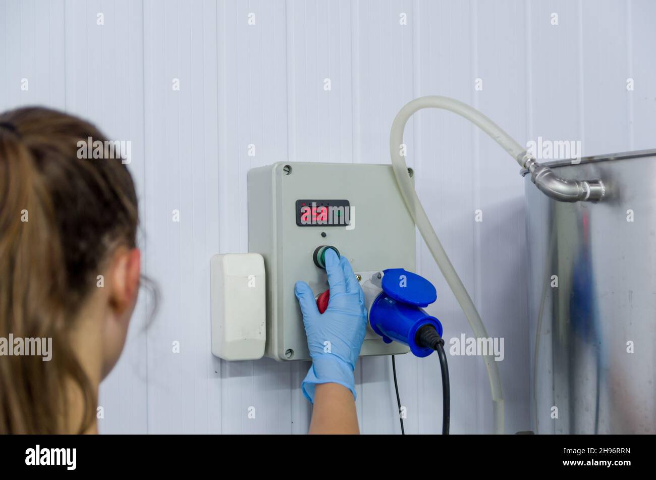 Frau, die in der Industrie arbeitet und den Tankthermostat justiert Stockfoto