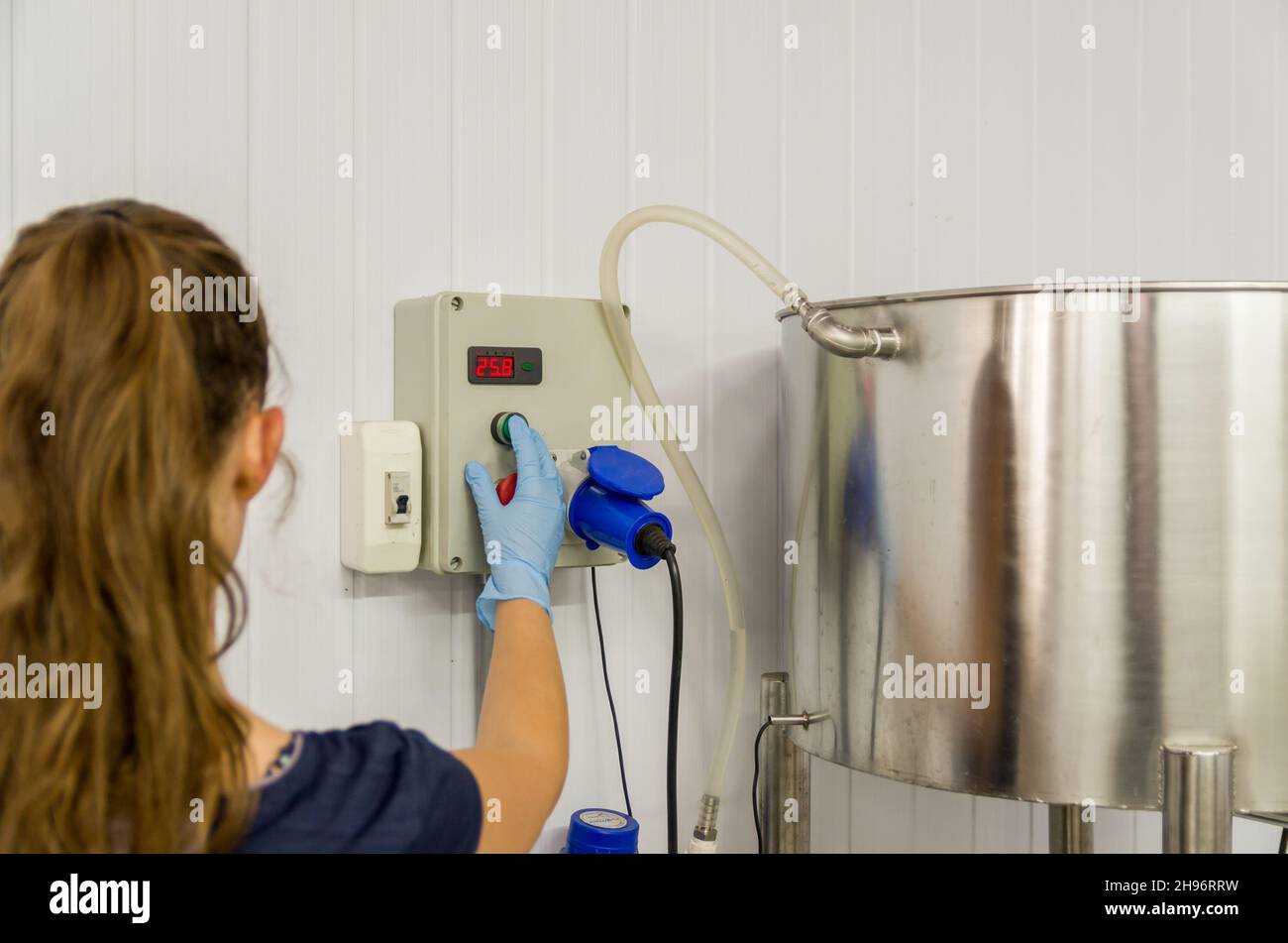 Frau, die in der Industrie arbeitet und den Tankthermostat justiert Stockfoto