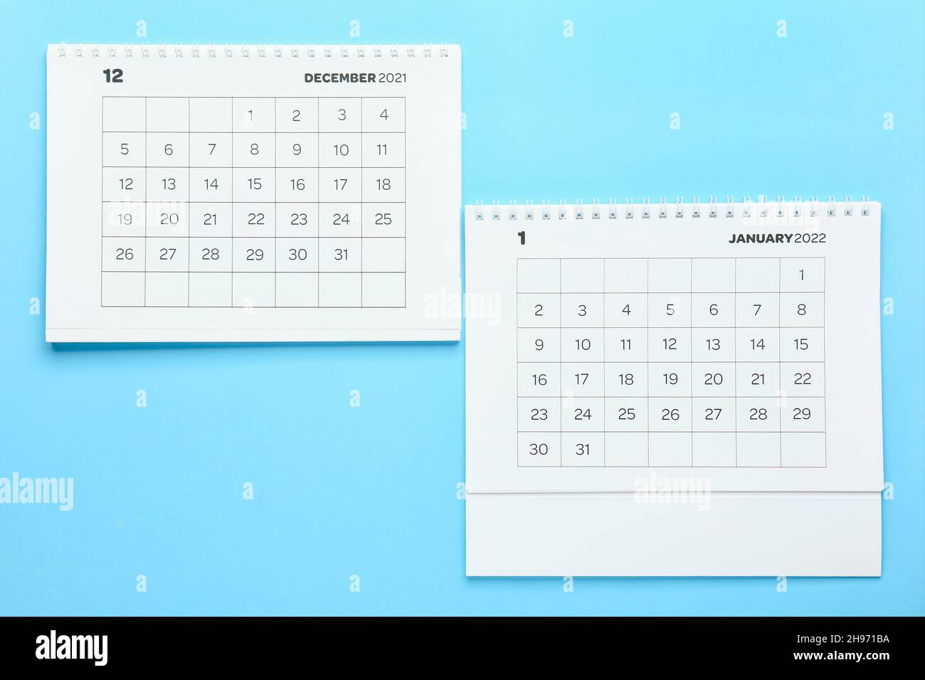 Klassische Papierkalender für Dezember 2021 und Januar 2022 auf farbigem Hintergrund Stockfoto