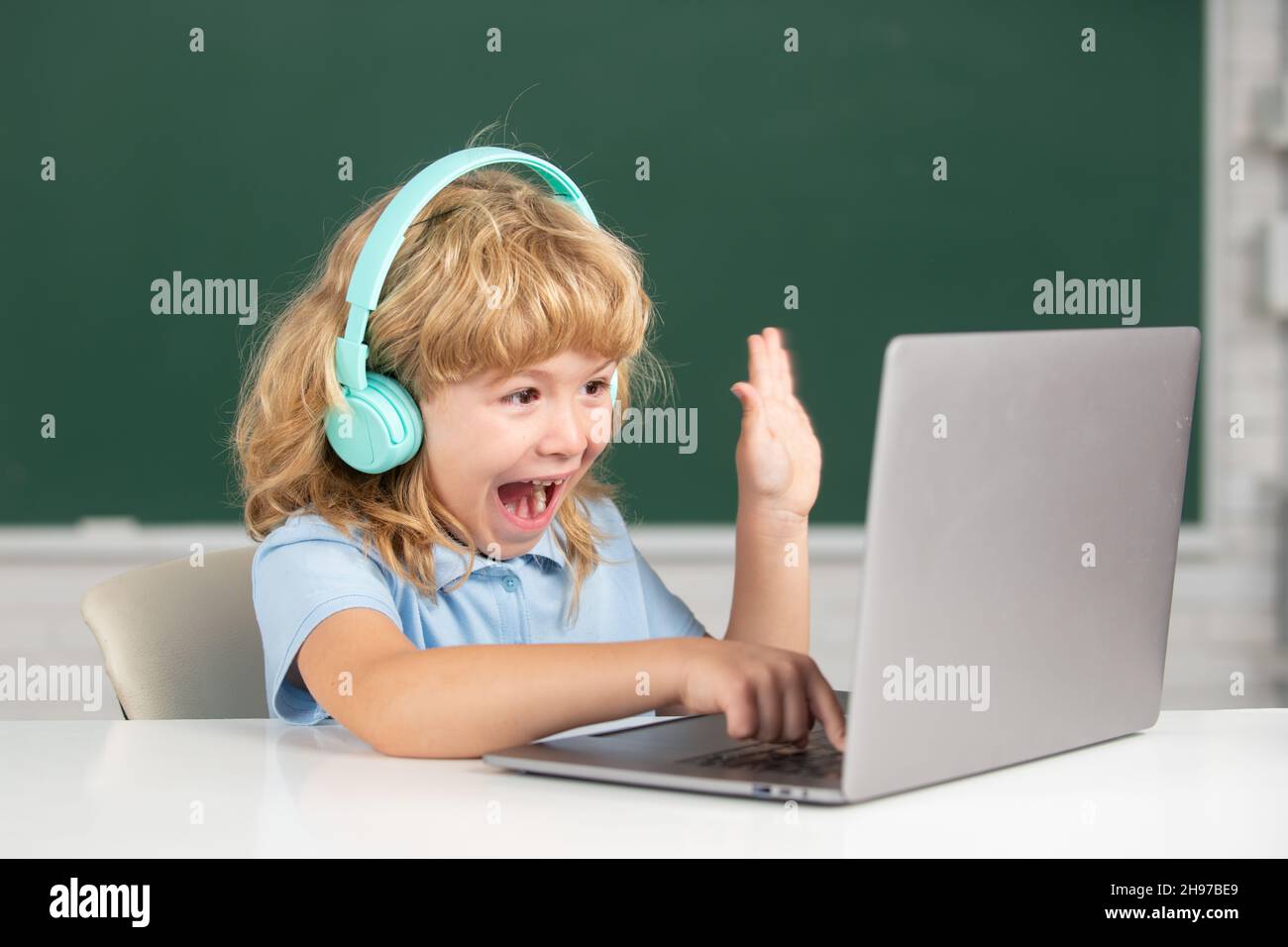 Aufgeregt Schuljunge, erstaunt Schüler trägt Kopfhörer schreiben auf Laptop, hören Audio-Unterricht am Computer. Videocall, E-Studie mit Tutor entfernt. Stockfoto