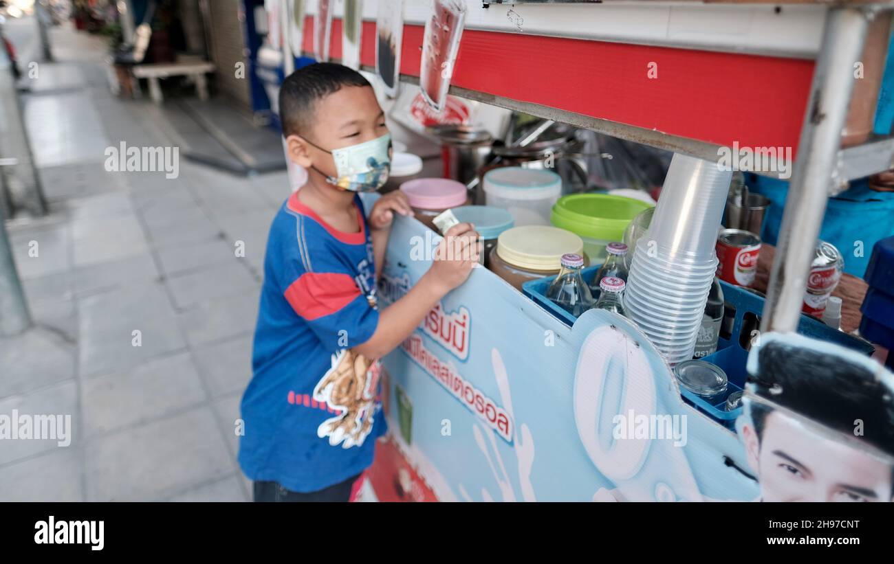 Geld in der Hand Junge Mann trägt Maske im Sweet Drinks Getränkewagen Soi Sukhumvit 22, Klong Ton, Khlong Toei, Bangkok Thailand Stockfoto