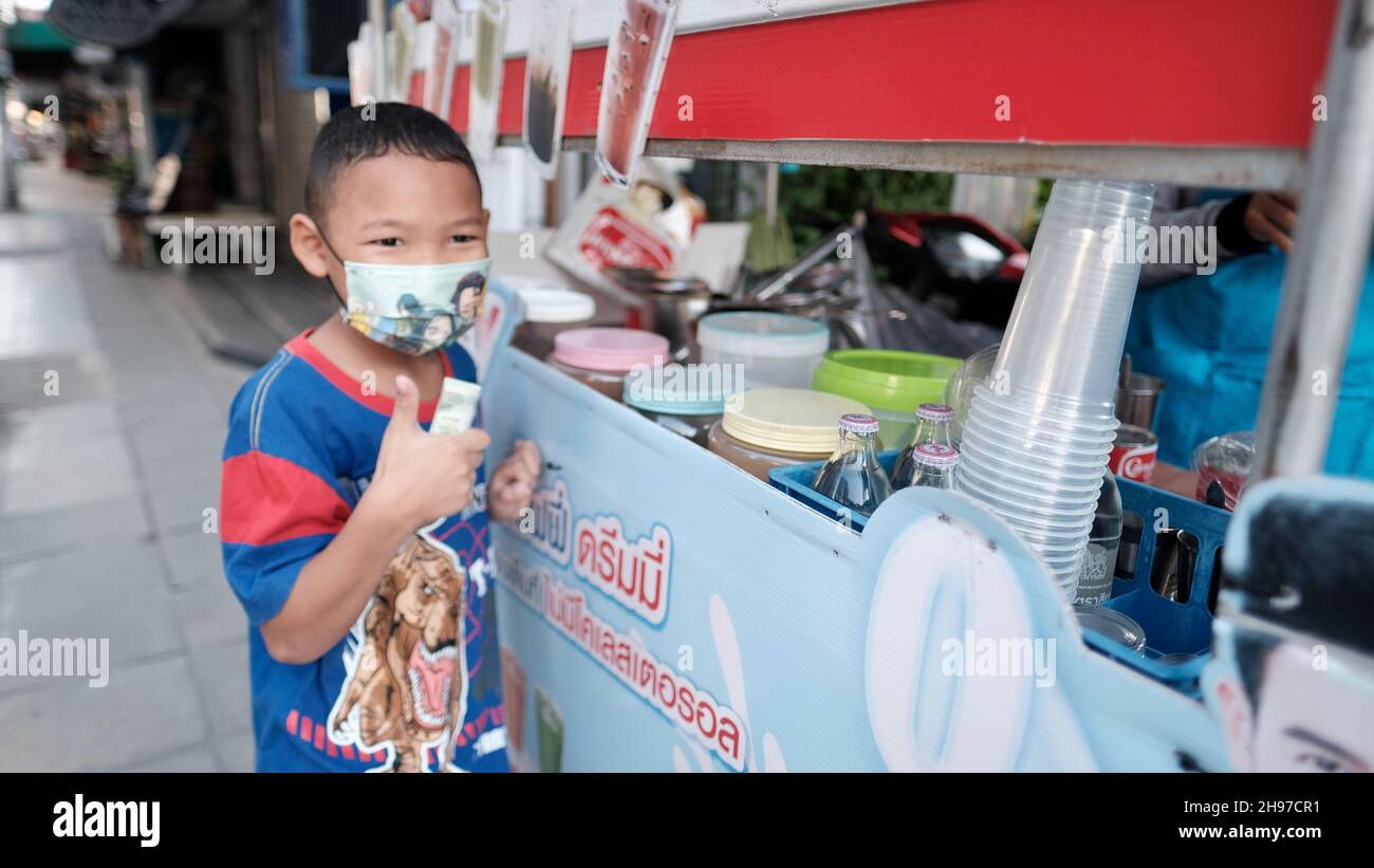 Geld in der Hand Junge Mann trägt Maske im Sweet Drinks Getränkewagen Soi Sukhumvit 22, Klong Ton, Khlong Toei, Bangkok Thailand Stockfoto