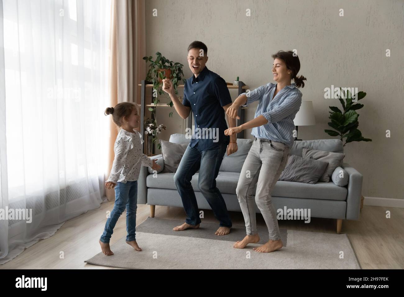 Aufgeregt paar Eltern lehren fröhliche Tochter Mädchen zu tanzen Stockfoto