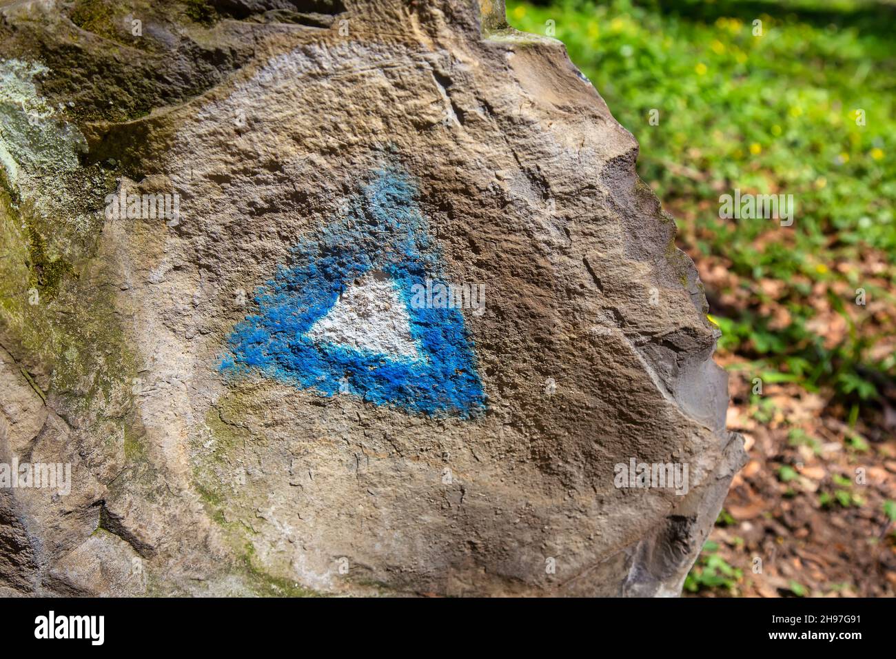 Wandern blaue Dreiecksfarbe Markierung auf einem Felsen mit Wanderer auf dem Weg. Stockfoto