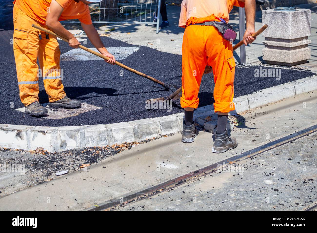 Handarbeit, Straßenreparaturen. Straßenbauarbeiter nivellieren frischen Asphalt. Stockfoto