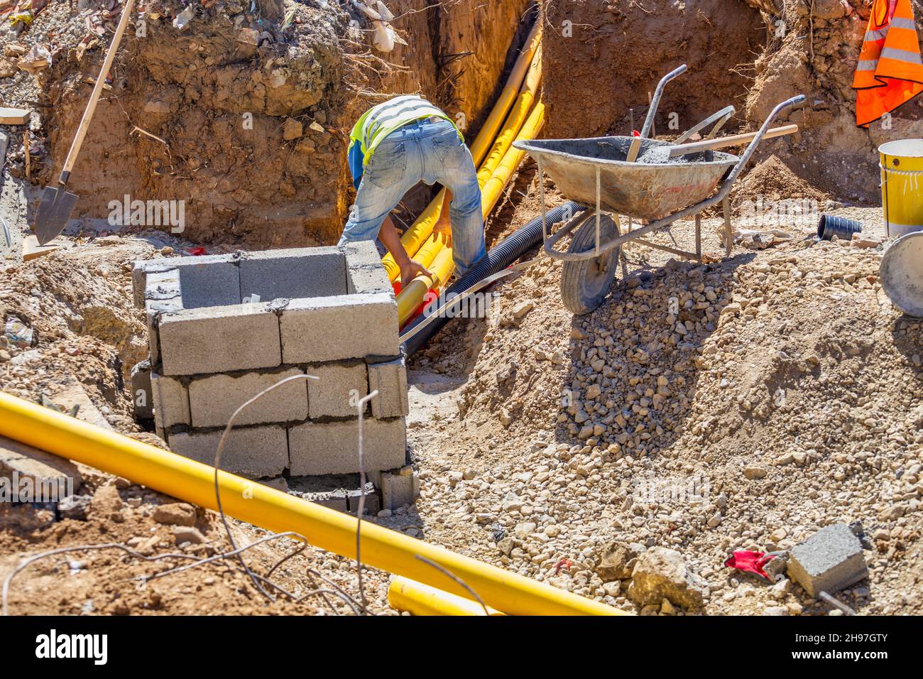 Arbeiter, die im Graben arbeiten und unterirdische Kommunikationen für das neue Gebäude installieren. Stockfoto