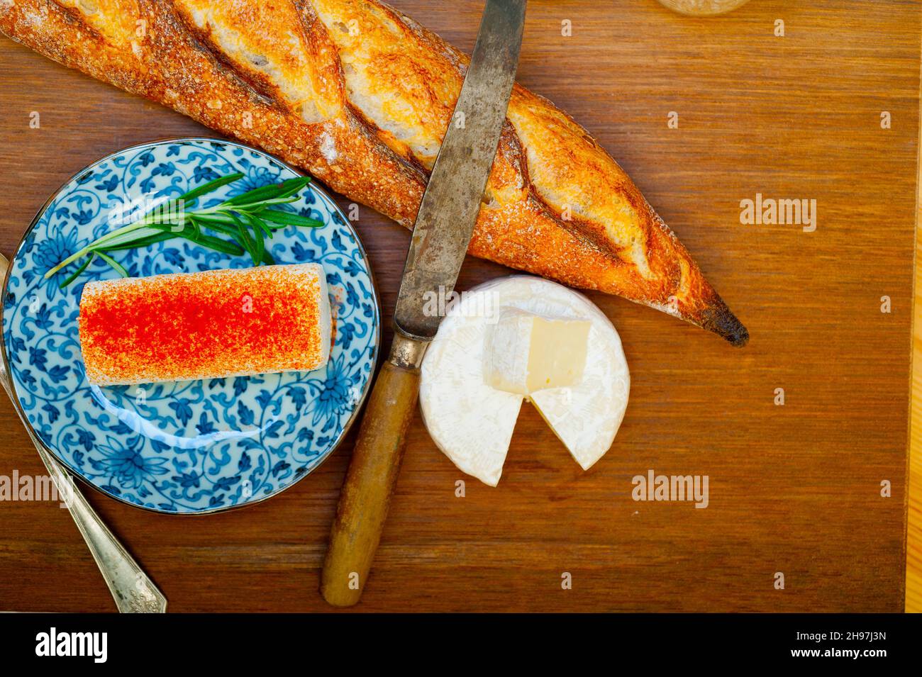 Französischer Käse und frisches Baguette auf einem Holzschneider Stockfoto