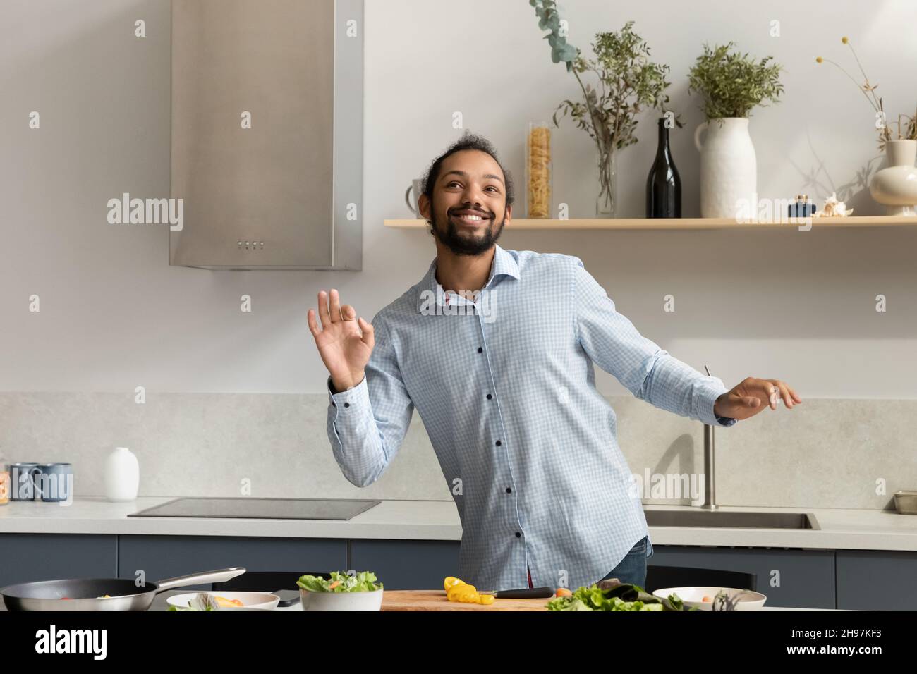 Glücklicher junger afroamerikanischer Mann, der tanzt und Essen kocht. Stockfoto