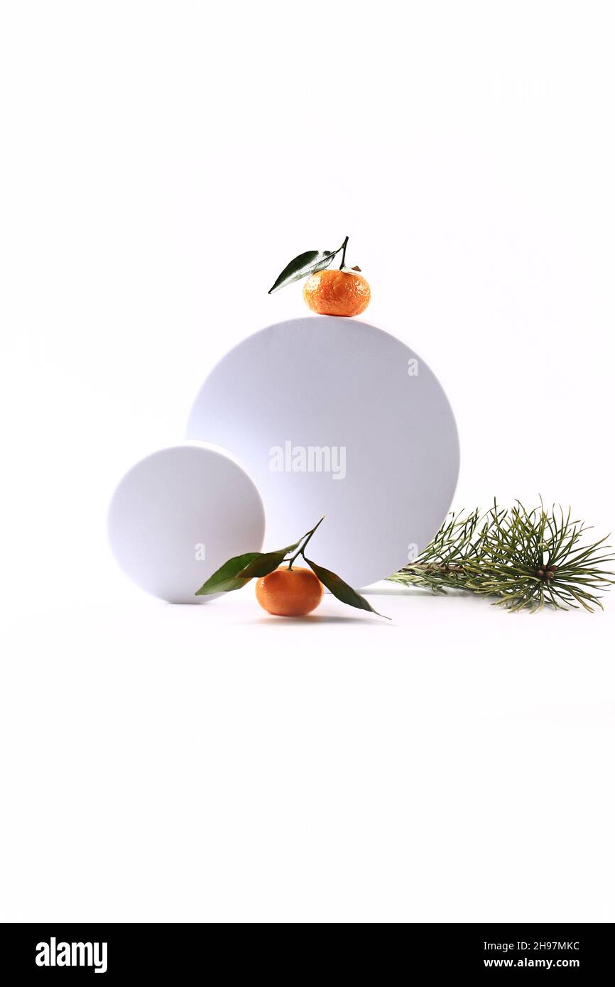 Mandarinen und ein Fichtenzweig auf weißem Hintergrund. Kreatives skandinavisches minimalistisches Weihnachtskonzert Stockfoto
