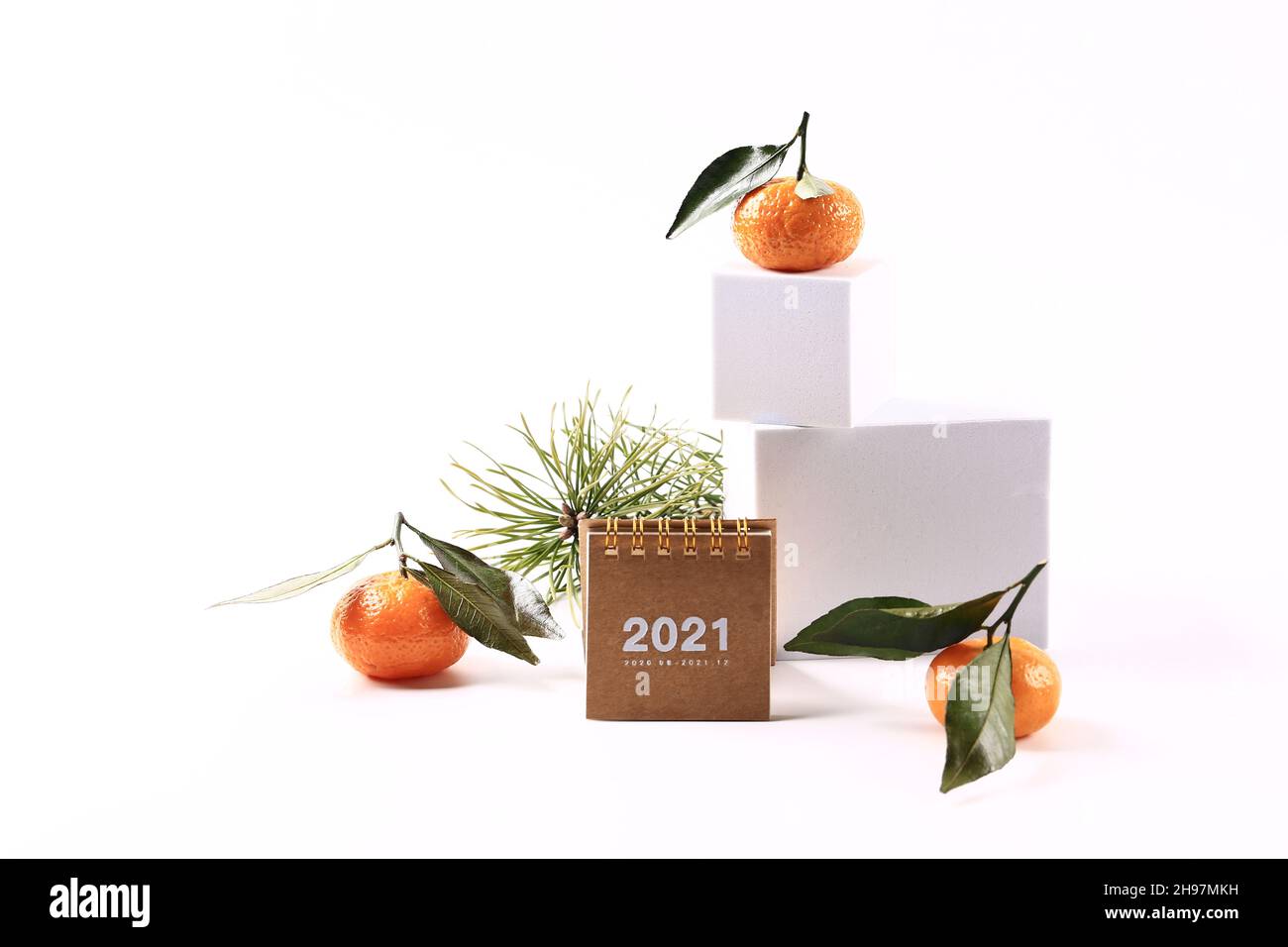 Mandarinen und ein Fichtenzweig, ein Kalender von 2021 und ein Buchstabe auf weißem Hintergrund. Kreatives skandinavisches minimalistisches Weihnachtskonzert Stockfoto