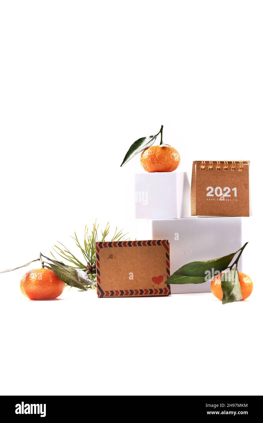 Mandarinen und ein Fichtenzweig, ein Kalender von 2020 und ein Buchstabe auf weißem Hintergrund. Kreatives skandinavisches minimalistisches Weihnachtskonzert Stockfoto