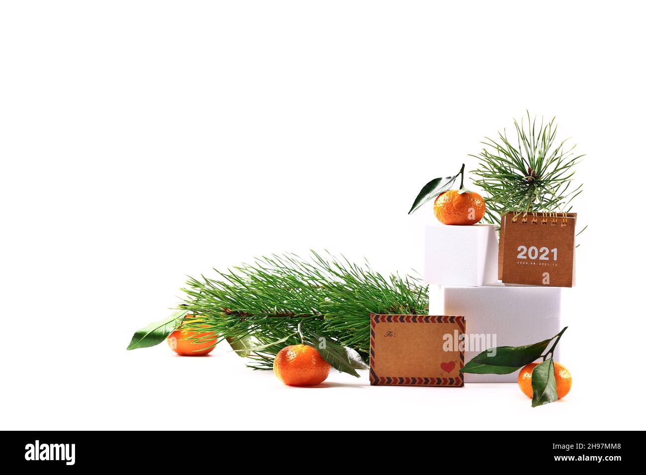 Mandarinen und ein Fichtenzweig, ein Kalender von 2021 und ein Buchstabe auf weißem Hintergrund. Kreatives skandinavisches minimalistisches Weihnachtskonzert Stockfoto