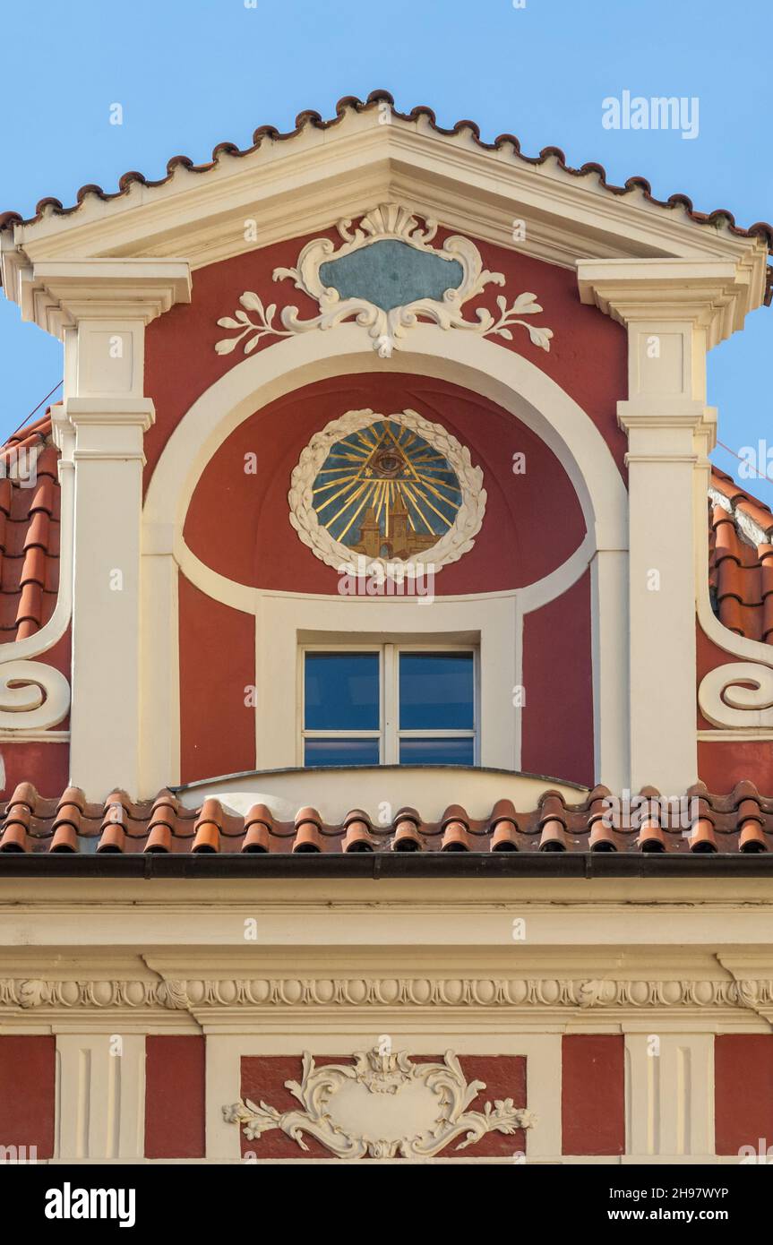 Ein farbenfrohes, historisches Gebäude in der Prager Malá Štupartská mit einem „Auge der Vorsehung“-Symbol, das prominent in einem Baldachin über einem Dachfenster angebracht ist Stockfoto
