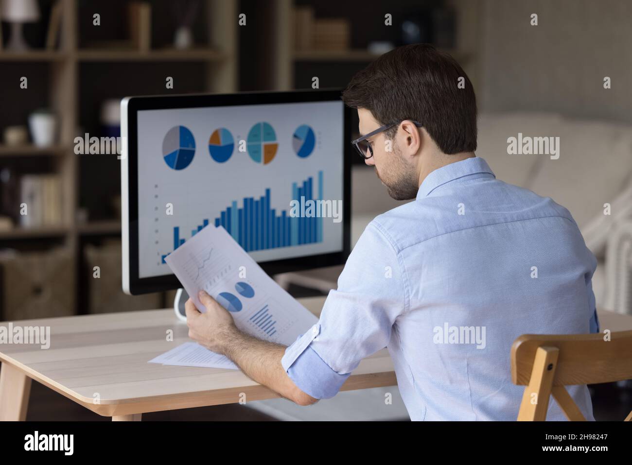 Fokussierter Millennial-Business-Mann, der Marketingberichte auf einem Desktop-Monitor analysiert Stockfoto