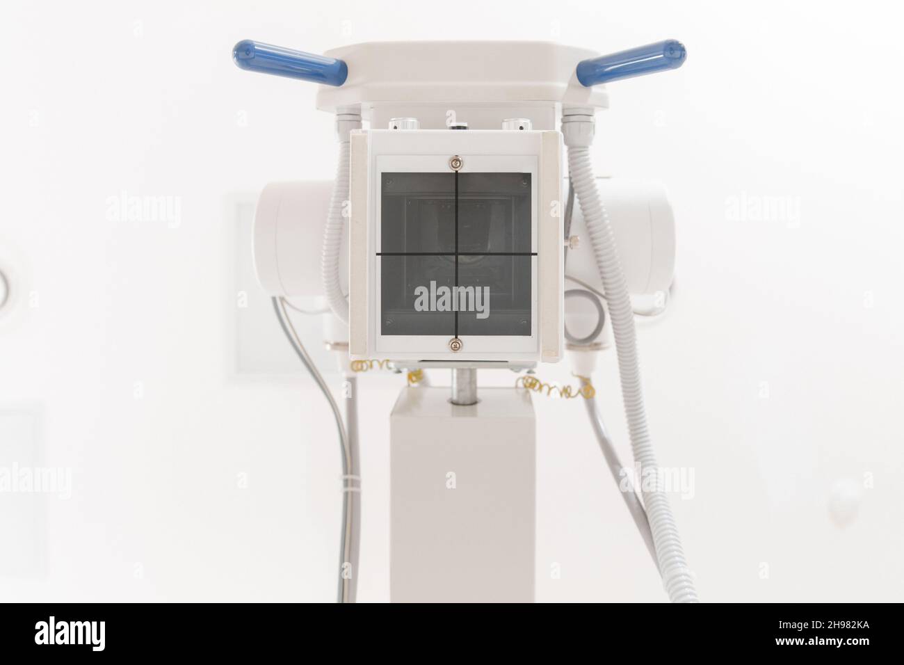 Röntgenabteilung im modernen Krankenhaus. Röntgenraum mit Scangerät und leerem Bett. Techniker, der ein Röntgengerät anpasst. Scannen von Brust, Herz Stockfoto