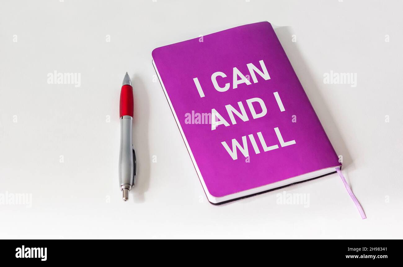 Ich kann und werde auf einem farbigen Notizbuch und einem weißen Hintergrund neben einem Stift geschrieben. Stockfoto