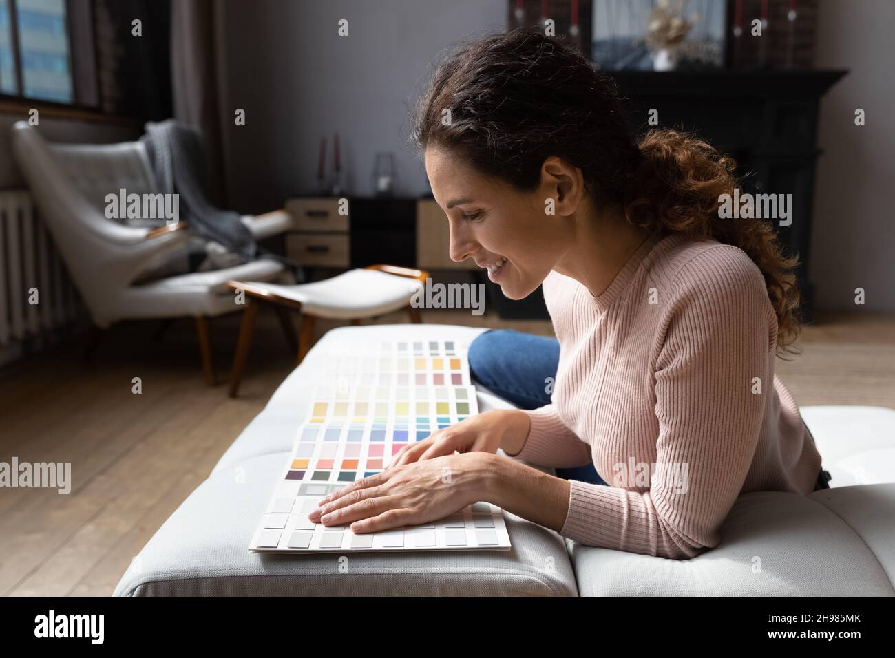 Lächelnde Frau Wahl Farbe aus Proben Katalog, Vorbereitung für die Renovierung Stockfoto