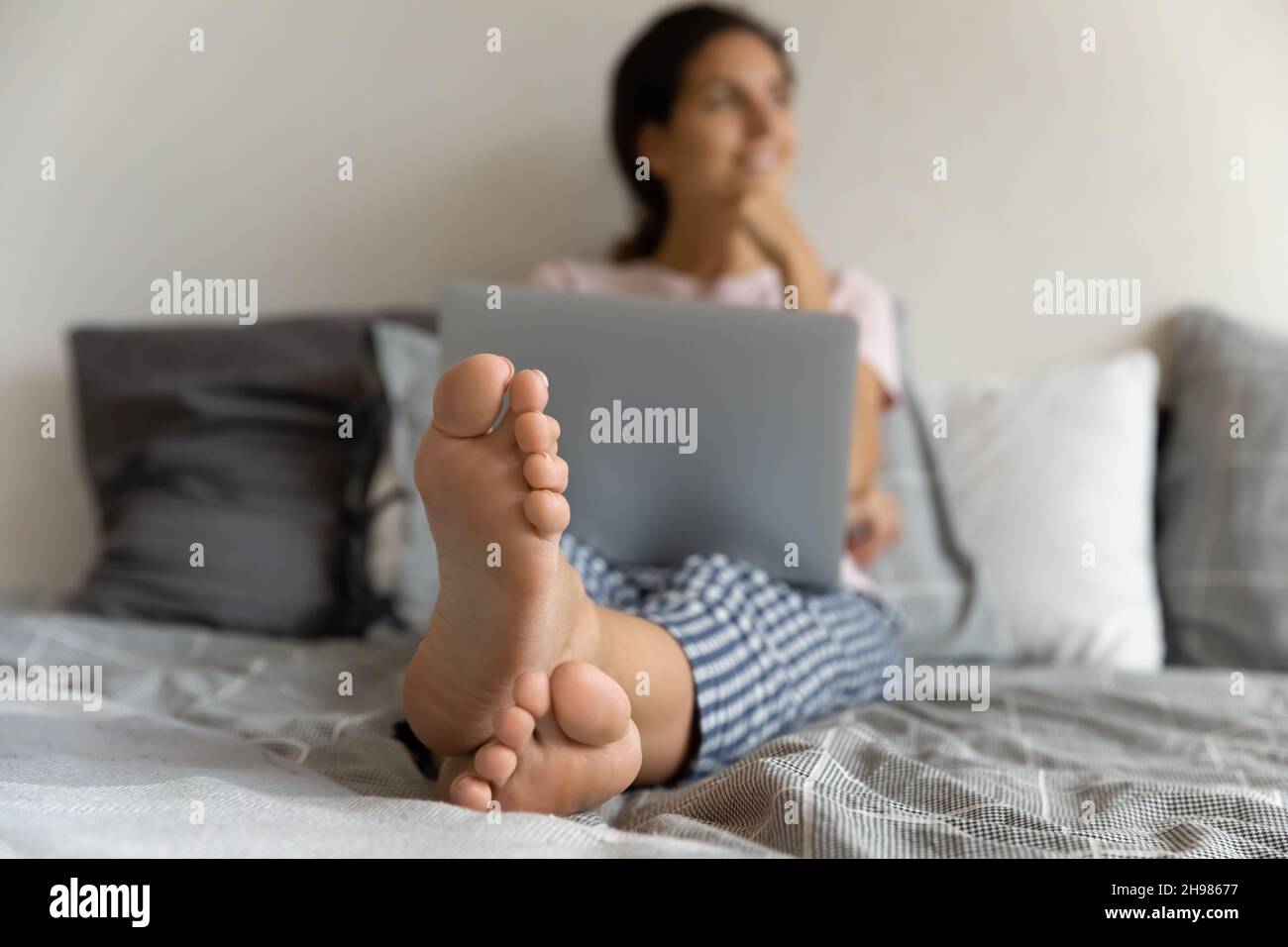 Nahaufnahme der verträumten Frau, die auf dem Bett entspannt sitzt Stockfoto