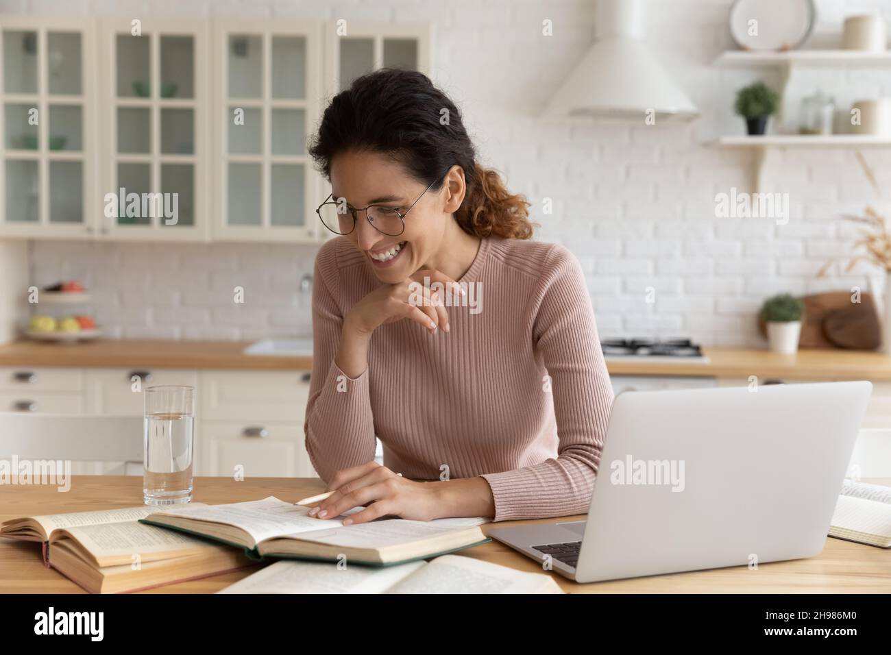 Lächelnde Frau in Brille, die zu Hause studiert, Buch liest Stockfoto