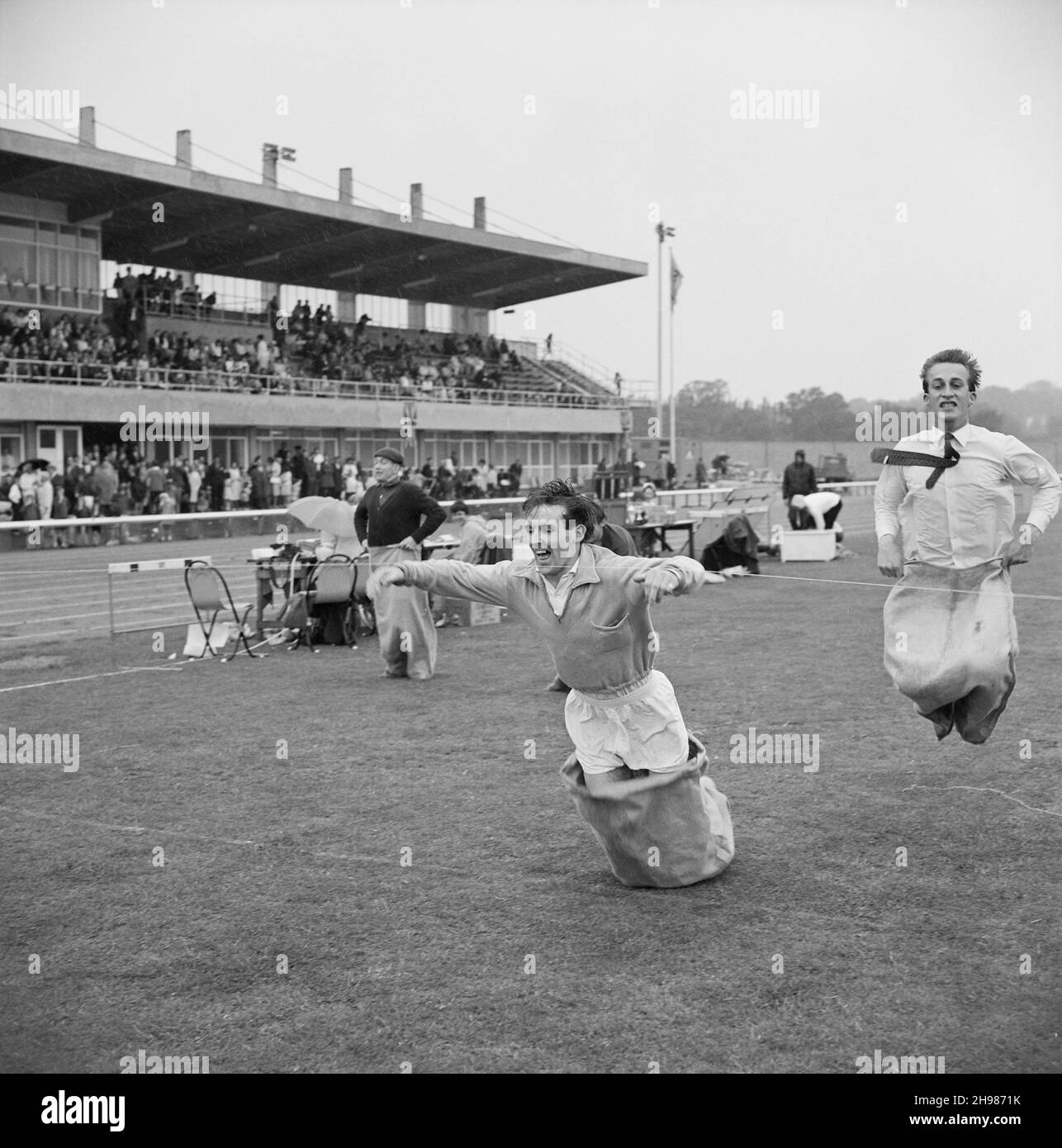 Copthall Stadium, Hendon, Barnett, London, 25/06/1966. Zwei Männer springen beim jährlichen Laing Sports Day im Copthall Stadium auf die Ziellinie des Männer-Sack-Rennens zu. Im Jahr 1966 fand am 25th. Juni der jährliche Laing Employees' Sports Day im Copthall Stadium in Hendon statt. Es war das erste Mal, dass die Veranstaltung dort stattfand, nachdem zuvor der Laing Sports Ground in Elstree stattgefunden hatte. Eine Reihe von Veranstaltungen umfasste Leichtathletik und einen Fußballwettbewerb, und die Teilnehmer reisten von den regionalen Büros und Standorten des Unternehmens, darunter aus Schottland und Carlisle. Es gab auch einen Kirmes, marc Stockfoto