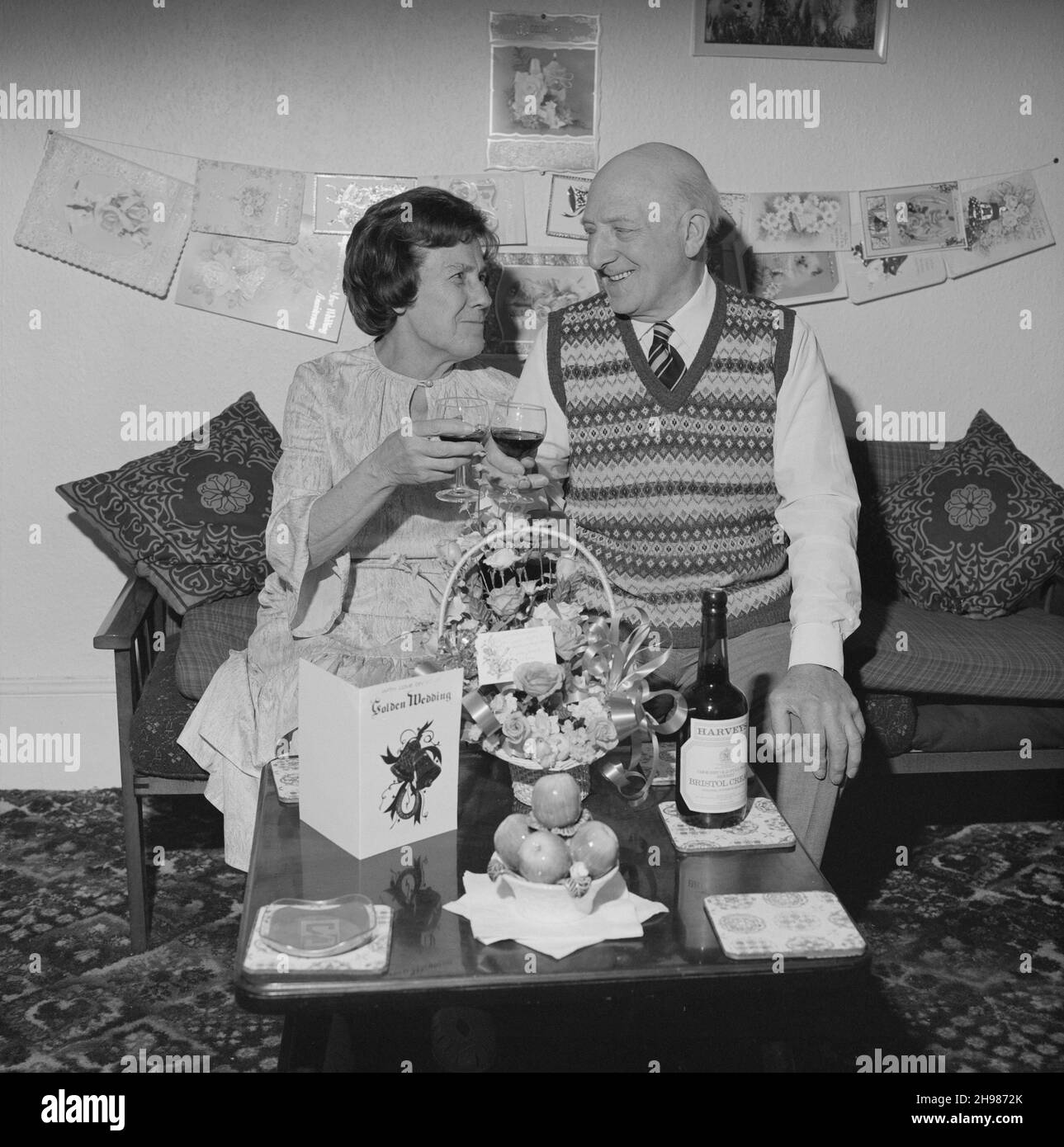 Herr und Frau Birtmead toasting zu ihrem goldenen Hochzeitstag, 26/04/1984. Herr und Frau Birtmead toasting zu ihrem goldenen Hochzeitstag, während sie in ihrem Haus zwischen Karten und Geschenken sitzen. Stockfoto