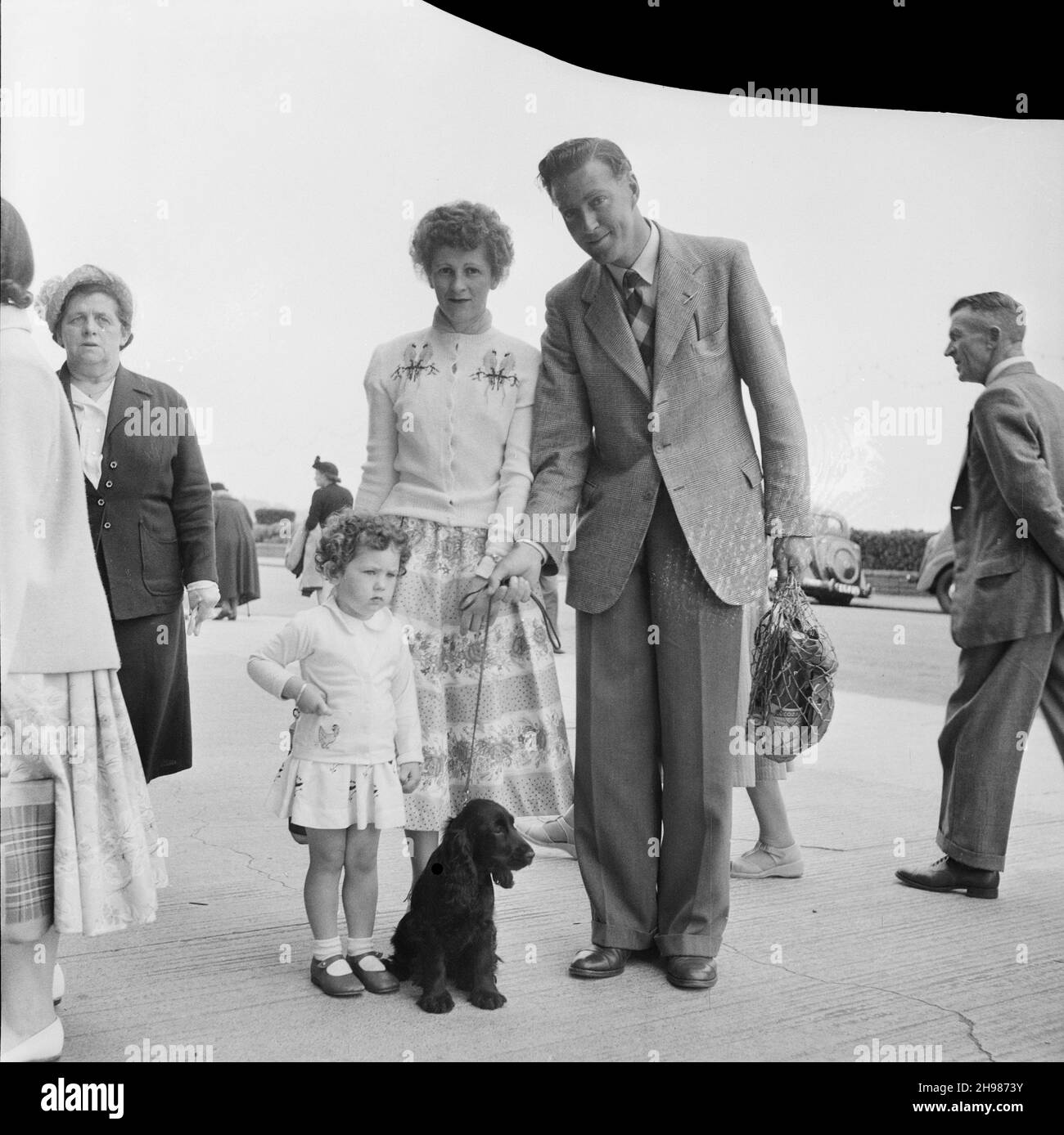 Felixstowe, Suffolk Coastal, Suffolk, 19/06/1954. Eine Familie mit einem jungen Mädchen und einem Hund posierte während einer Laing-Mitarbeiterreise nach Felixstowe. Im Jahr 1947, nach einer siebenjährigen Pause, hatte Laing seine „Ausflüge in die Umgebung“ für Mitarbeiter und ihre Familien wiederbelebt, wobei die Reisen im Mai und Juni stattfinden. Im Jahr 1954 waren sieben Ausflüge geplant, die über fünf Wochen im Mai und Juni stattfinden sollen. Diese Reise war für Mitarbeiter und ihre Familien aus den östlichen Grafschaften. Stockfoto