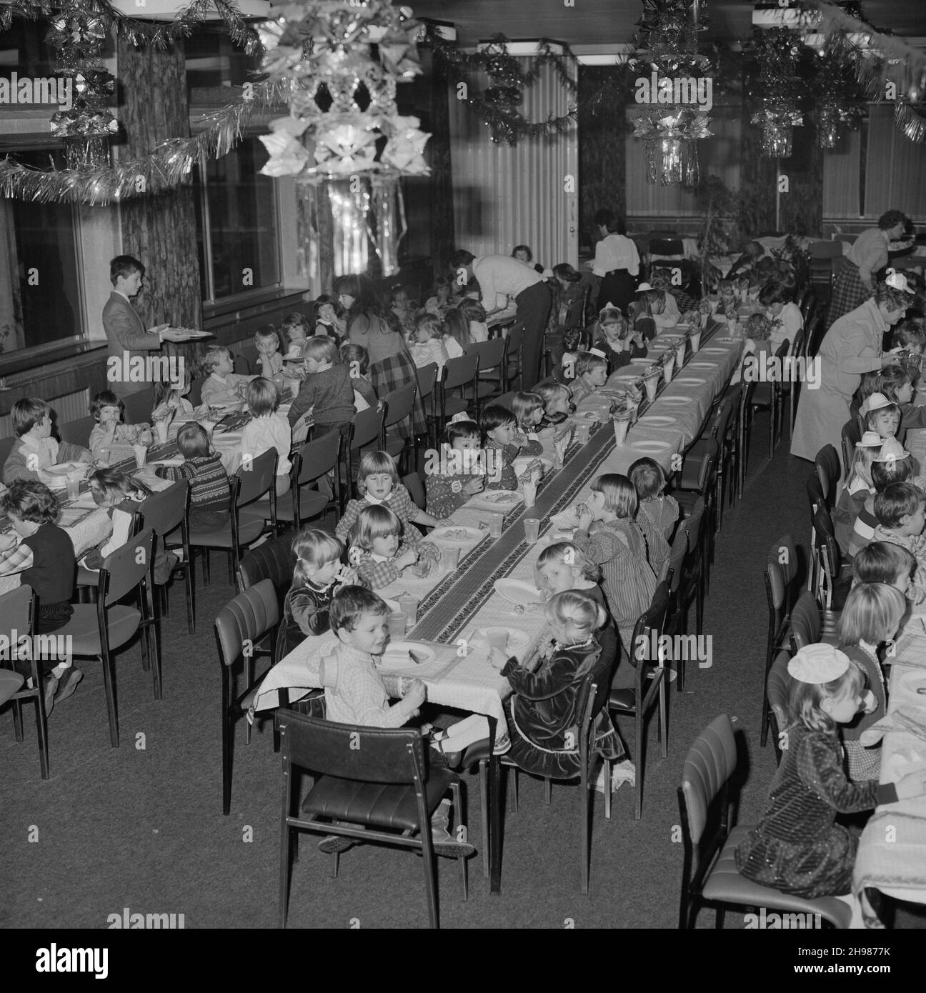 John Laing and Son Limited, Page Street, Mill Hill, Barnett, London, 15/12/1984. Kleine Kinder essen an langen Tischen während einer Weihnachtsfeier für Kinder in der Kantine von Laing's Mill Hill. Diese Weihnachtsfeier war für Kinder im Alter von vier bis sieben Jahren. Stockfoto