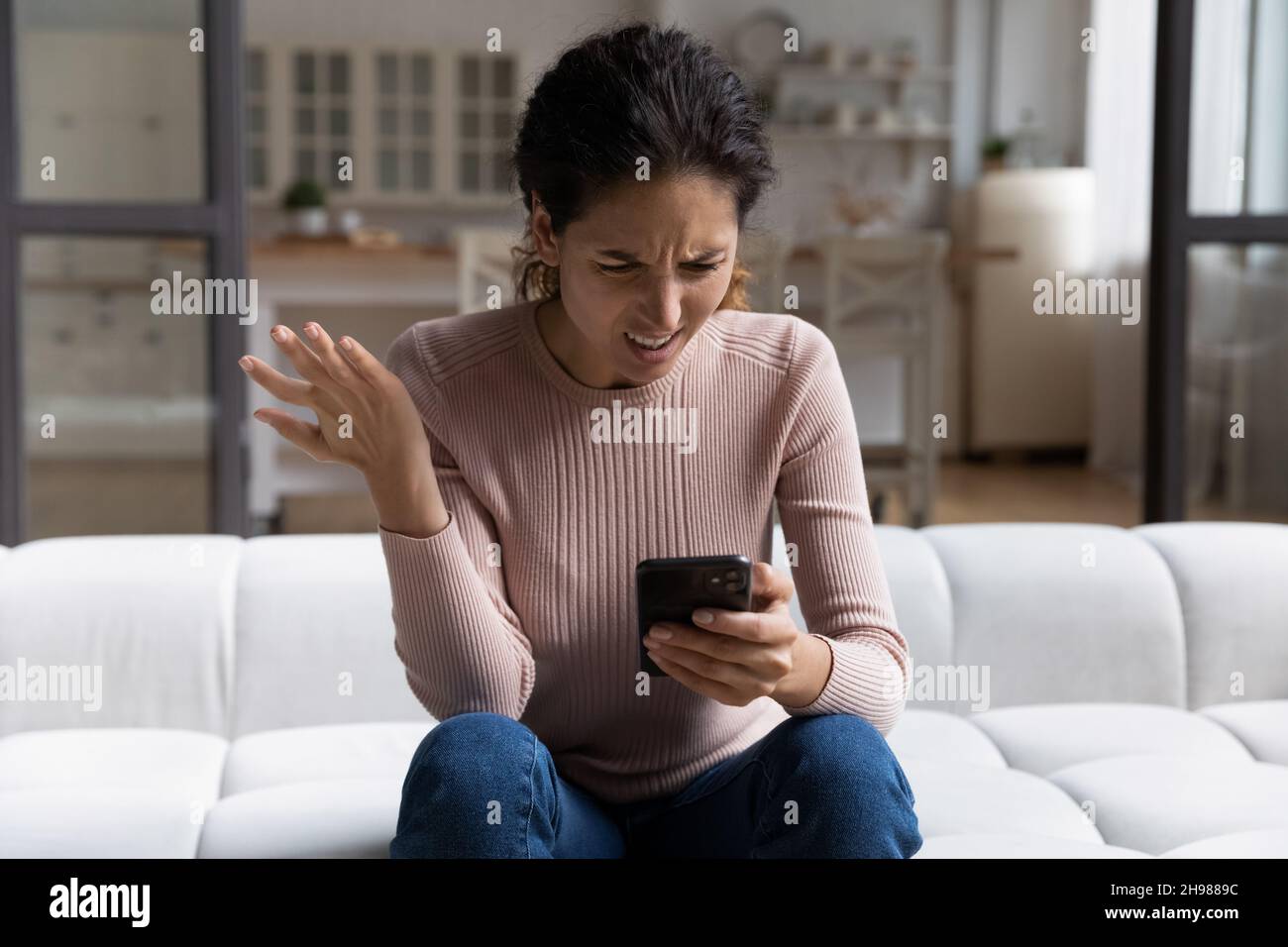 Verwirrt wütend Frau Blick auf Smartphone-Bildschirm, sitzen auf der Couch Stockfoto