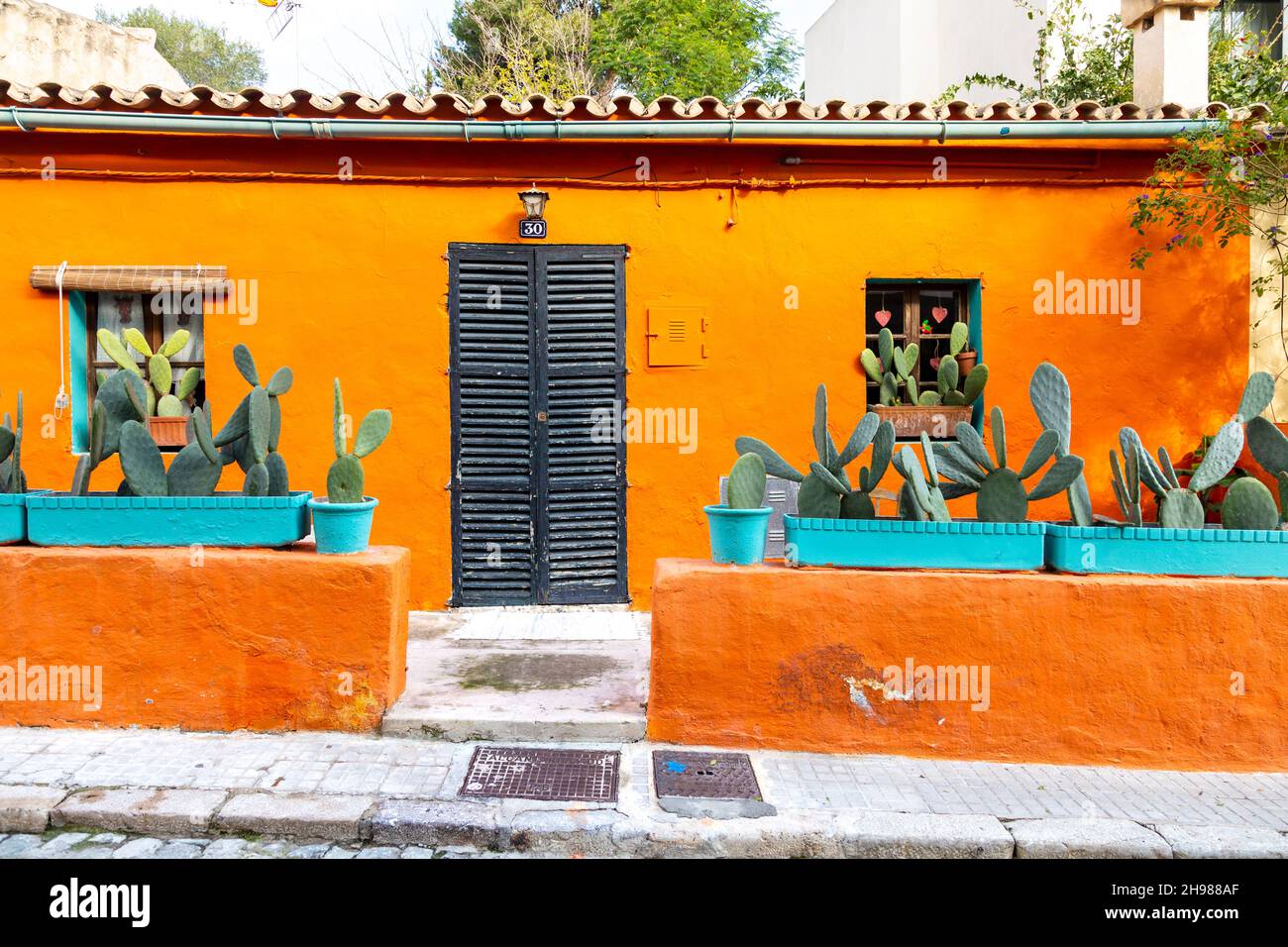 Außenansicht eines lebhaften orangefarbenen Hauses mit Topfkakteen in der Carrer del Polvorí, El Terreno, Palma, Mallorca, Spanien Stockfoto