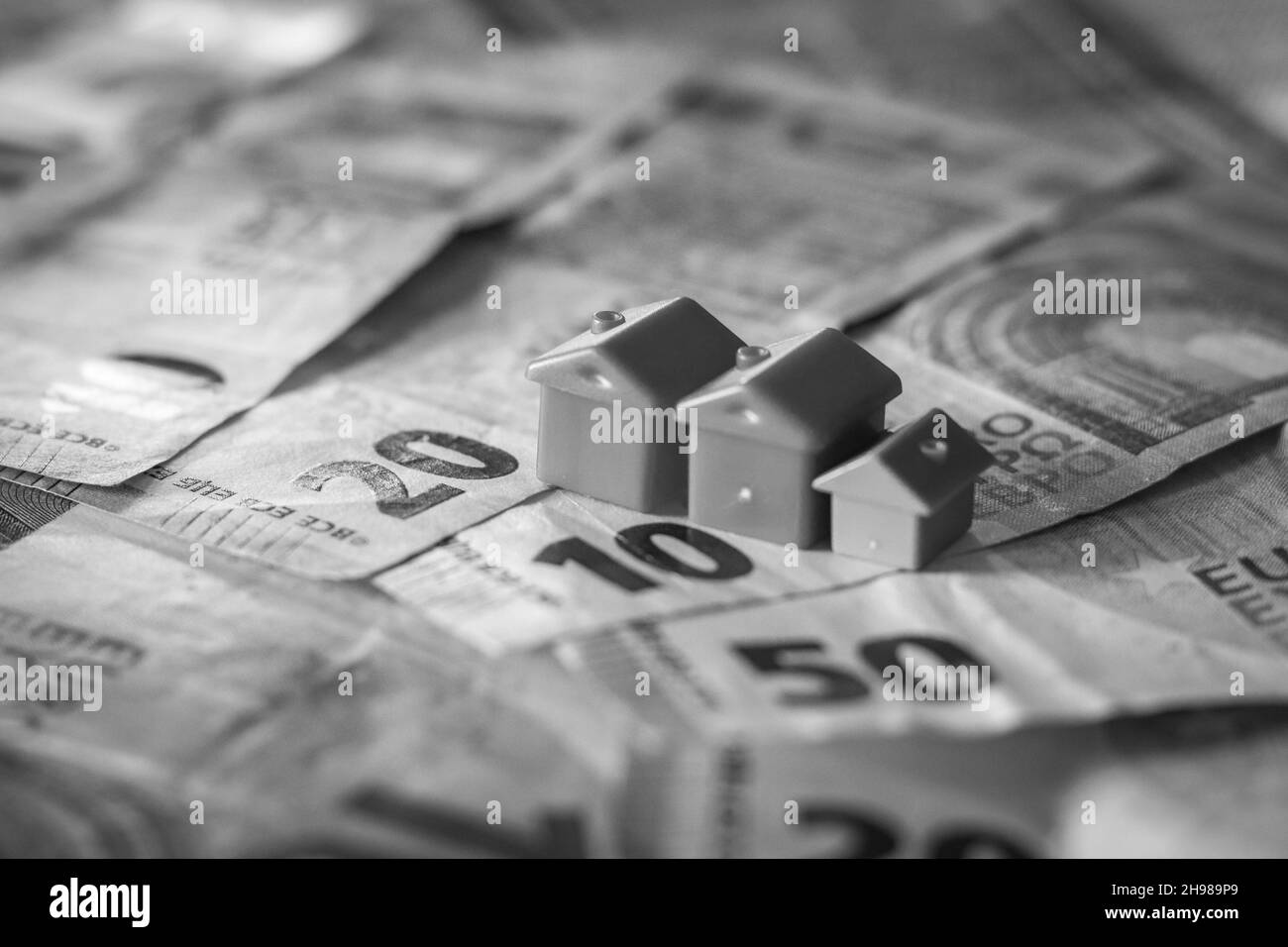 Tisch mit Euro-Banknoten bedeckt mit Häusern auf der Oberseite. Immobilieninvestitionskonzept Stockfoto