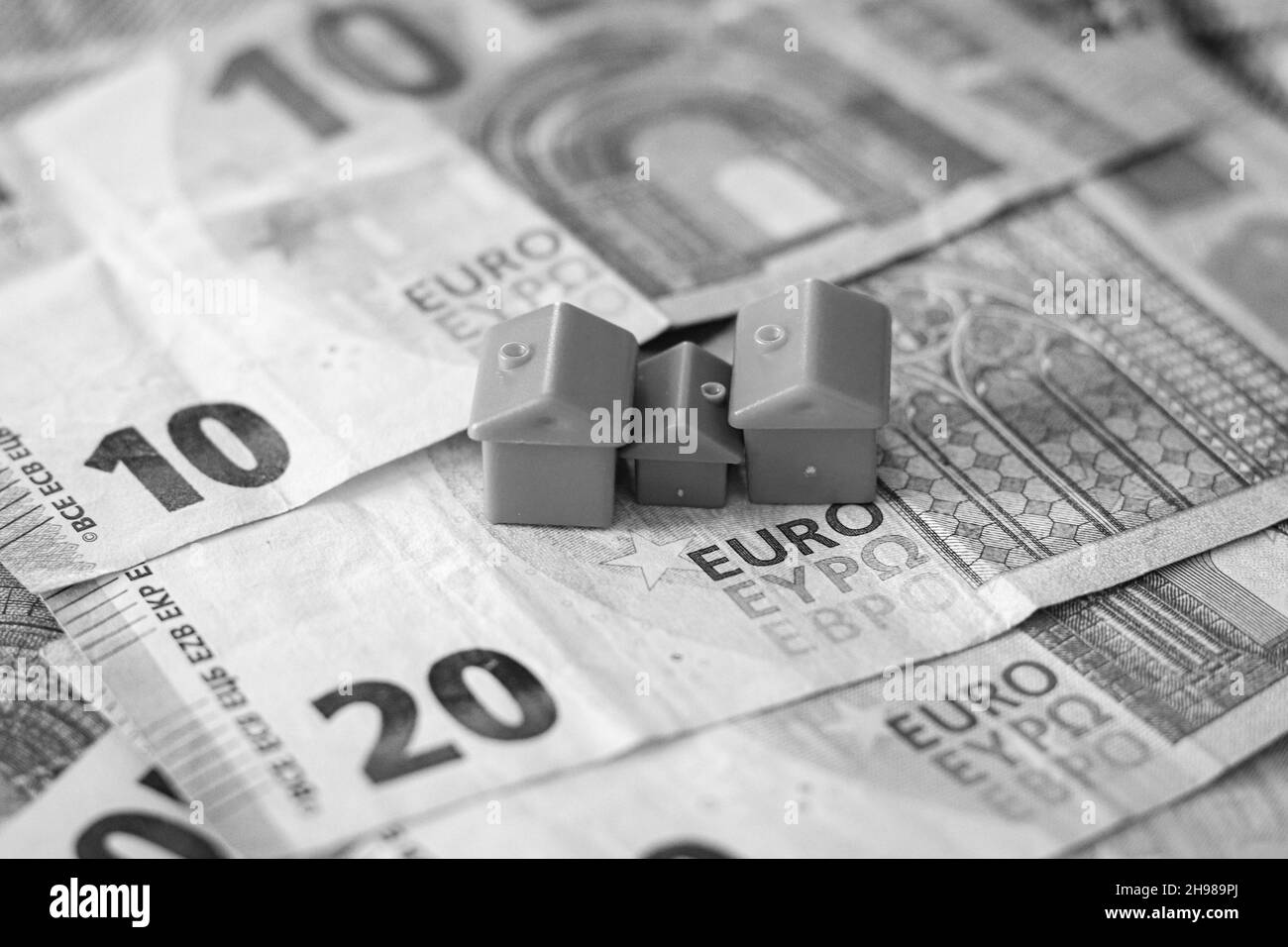 Tisch mit Euro-Banknoten bedeckt mit Häusern auf der Oberseite. Immobilieninvestitionskonzept Stockfoto