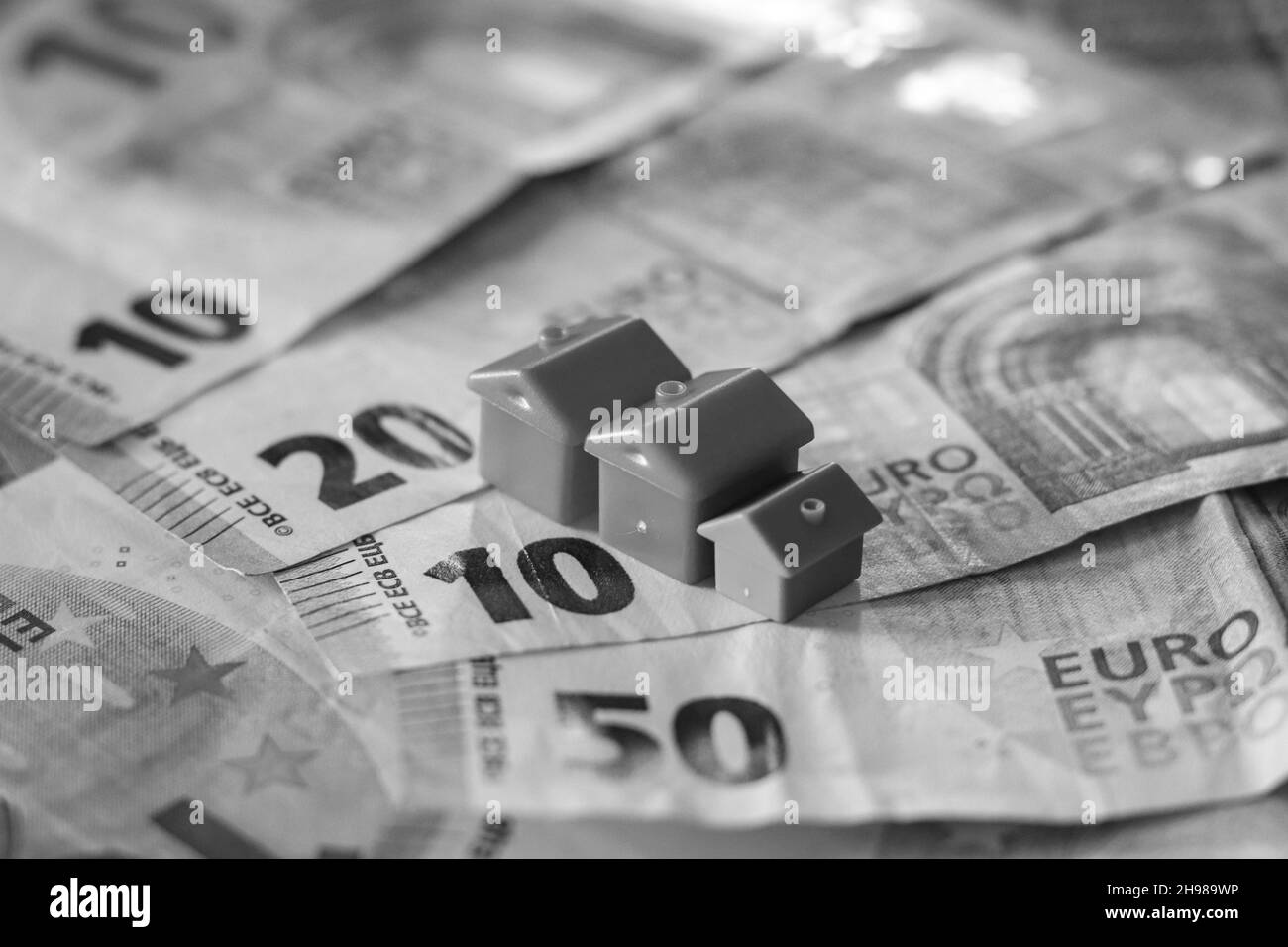 Tisch mit Euro-Banknoten bedeckt mit Häusern auf der Oberseite. Immobilieninvestitionskonzept Stockfoto