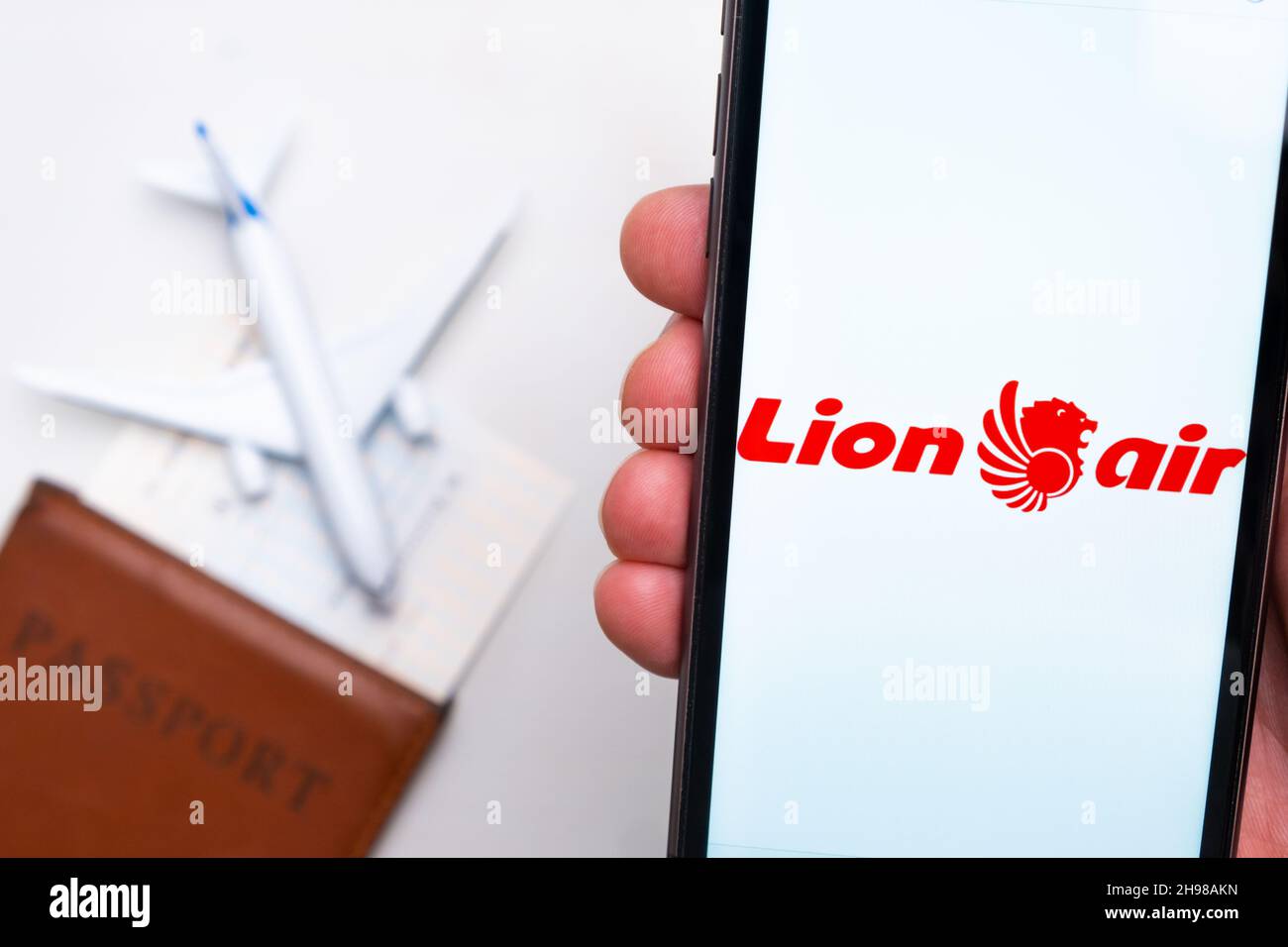 Lion Air Airline-Logo auf dem Handybildschirm mit einem Flugzeug, einem Reisepass und einer Bordkarte im Hintergrund. Das Konzept der mobilen Anwendung der Fluggesellschaften. November 2021, San Francisco, USA Stockfoto