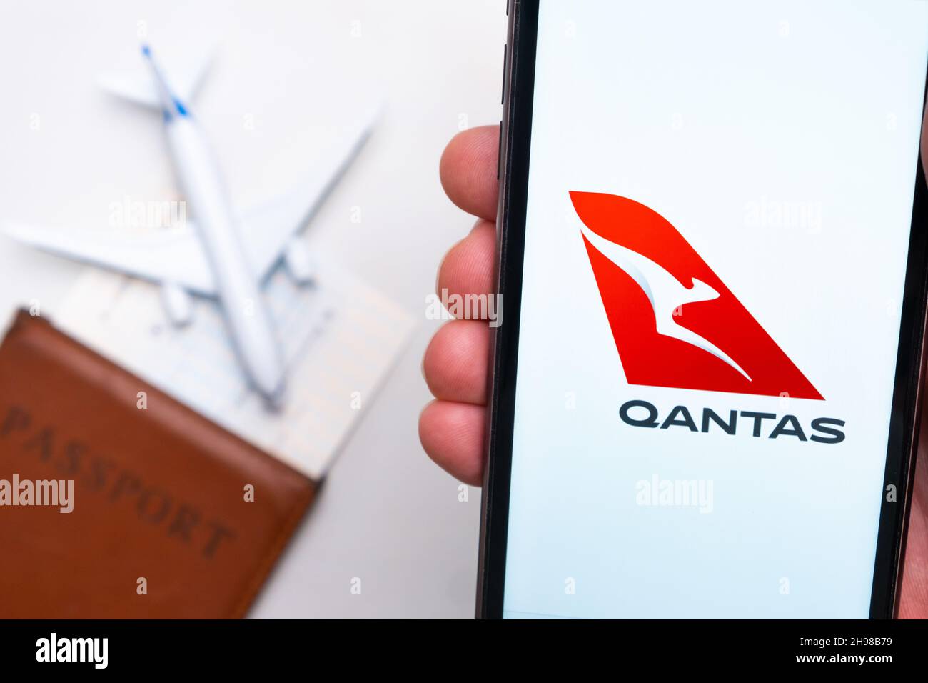 Qantas Airline-Logo auf dem Handybildschirm mit einem Flugzeug, einem Reisepass und einer Bordkarte im Hintergrund. Das Konzept der mobilen Anwendung der Fluggesellschaften. November 2021, San Francisco, USA Stockfoto