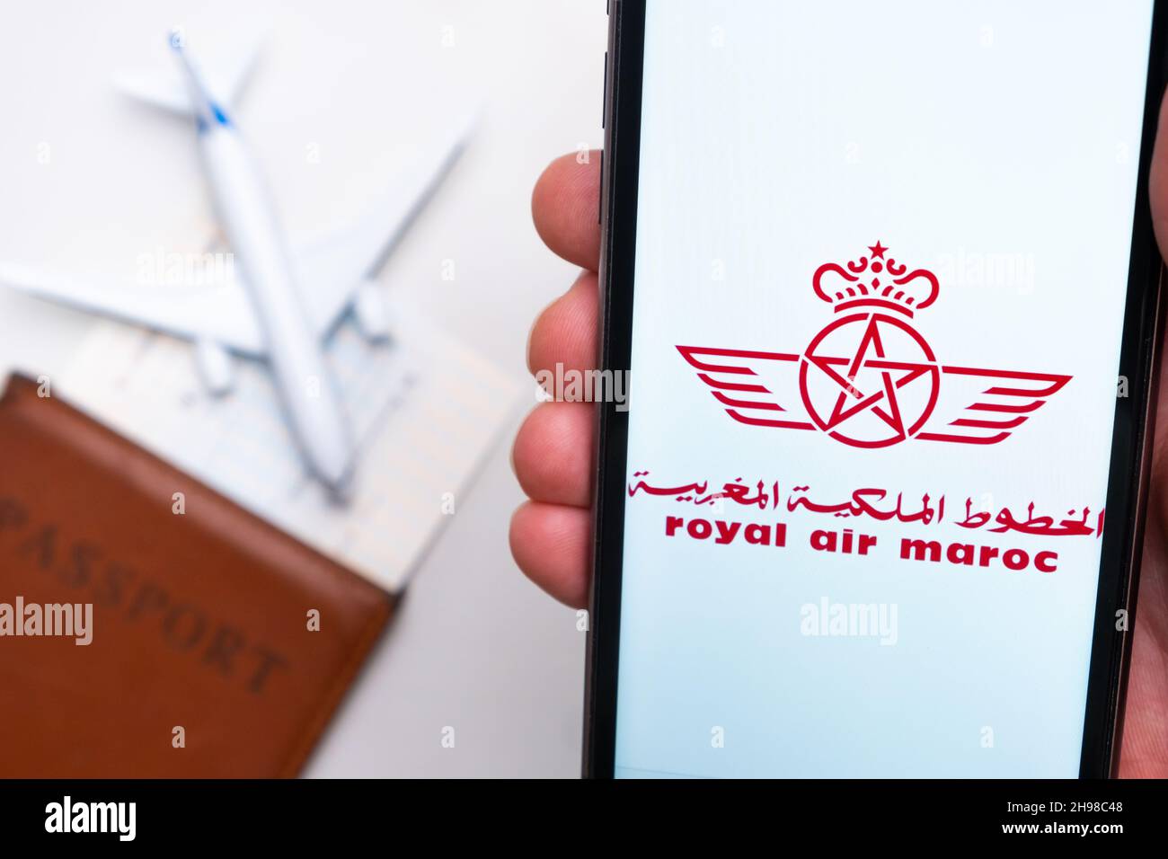 Royal Air Maroc Airline-Logo auf dem Handybildschirm mit Flugzeug, Reisepass und Bordkarte im Hintergrund. Das Konzept der mobilen Anwendung der Fluggesellschaften. November 2021, San Francisco, USA Stockfoto