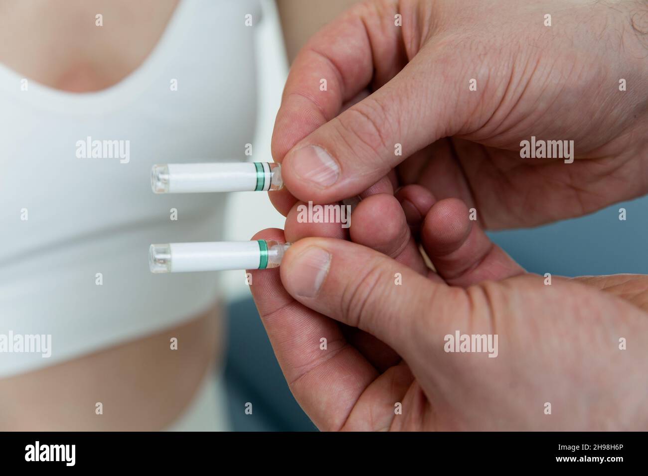 Der Arzt hält kleine Ampullen in den Händen. Nahaufnahme einer kleinen Ampulle mit einem Impfstoff in der Hand des Arztes. Reagenzglas für Allergietest halten. Allergietests Stockfoto