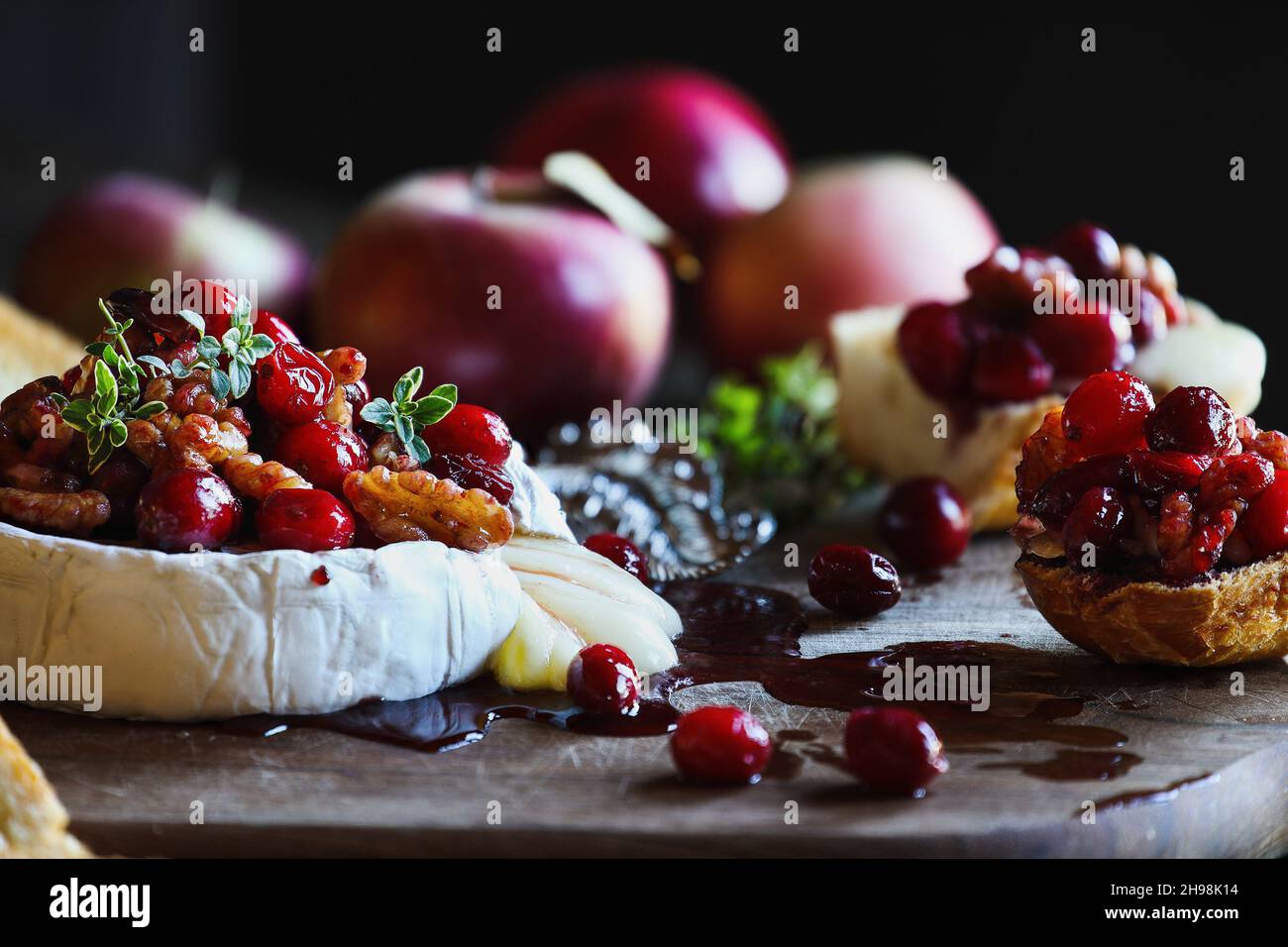 Gebackenen Camembert Brie Käse mit Cranberry, Honig, Balsamico-Essig und Nuss genießen und mit Thymian garniert. Serviert mit gerösteten Brotscheiben und Fr. Stockfoto