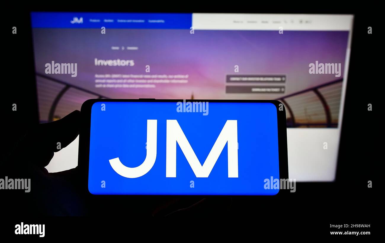 Person mit Mobiltelefon und Logo des britischen Chemieunternehmens Johnson Matthey plc auf dem Bildschirm vor der Webseite. Konzentrieren Sie sich auf die Telefonanzeige. Stockfoto