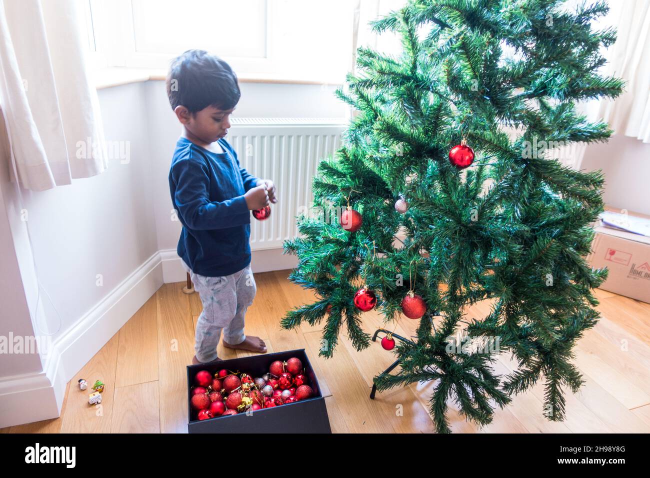 Indischer Junge im Alter von 3 Jahren, der Weihnachtsbaum mit Kugeln