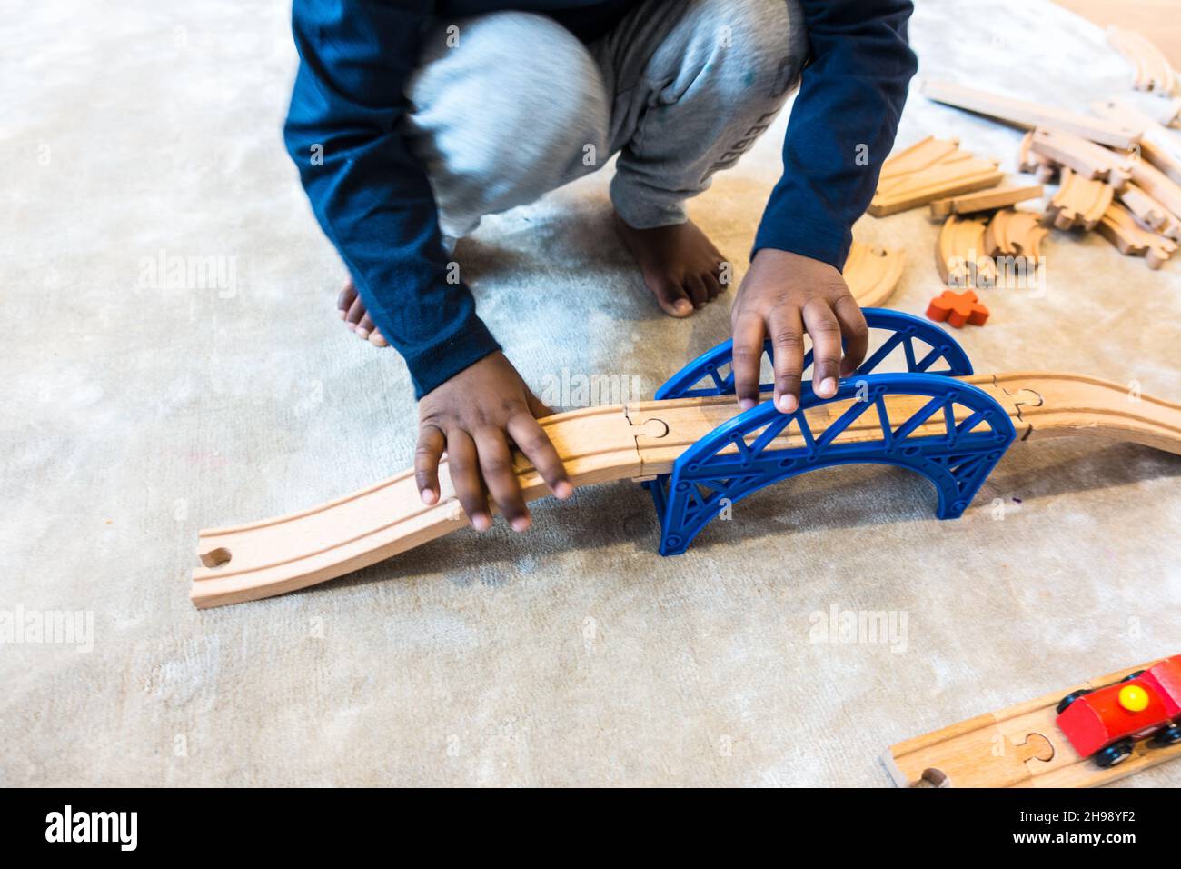 Junge spielt mit Zug Spielzeug. Indischer Junge im Alter von 3 Jahren, der mit einer hölzernen Eisenbahnstrecke und einem Zugsatz spielt Stockfoto