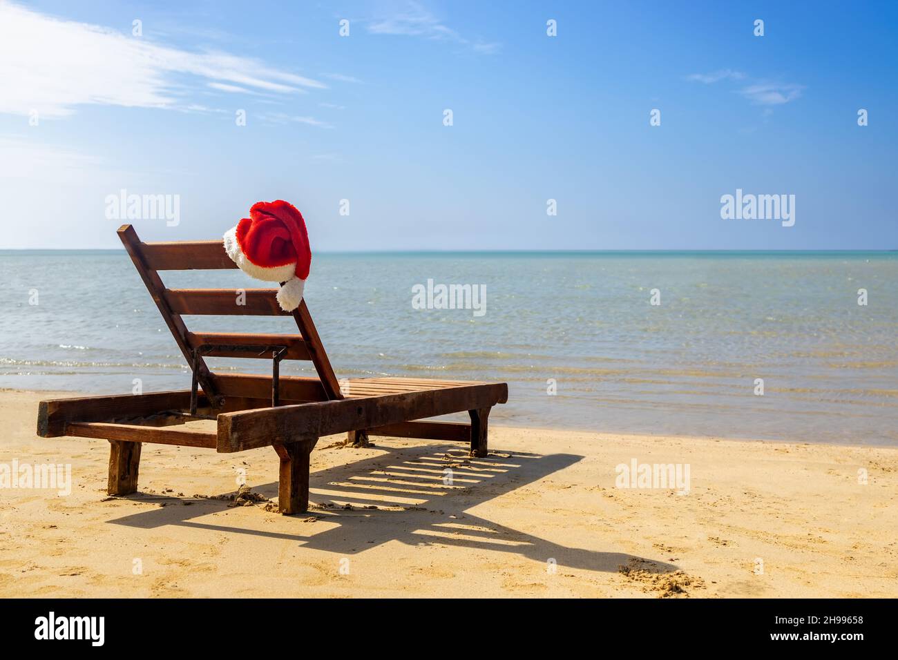Weihnachtsmann Hut auf Stuhl Lounge am Strand Stockfoto
