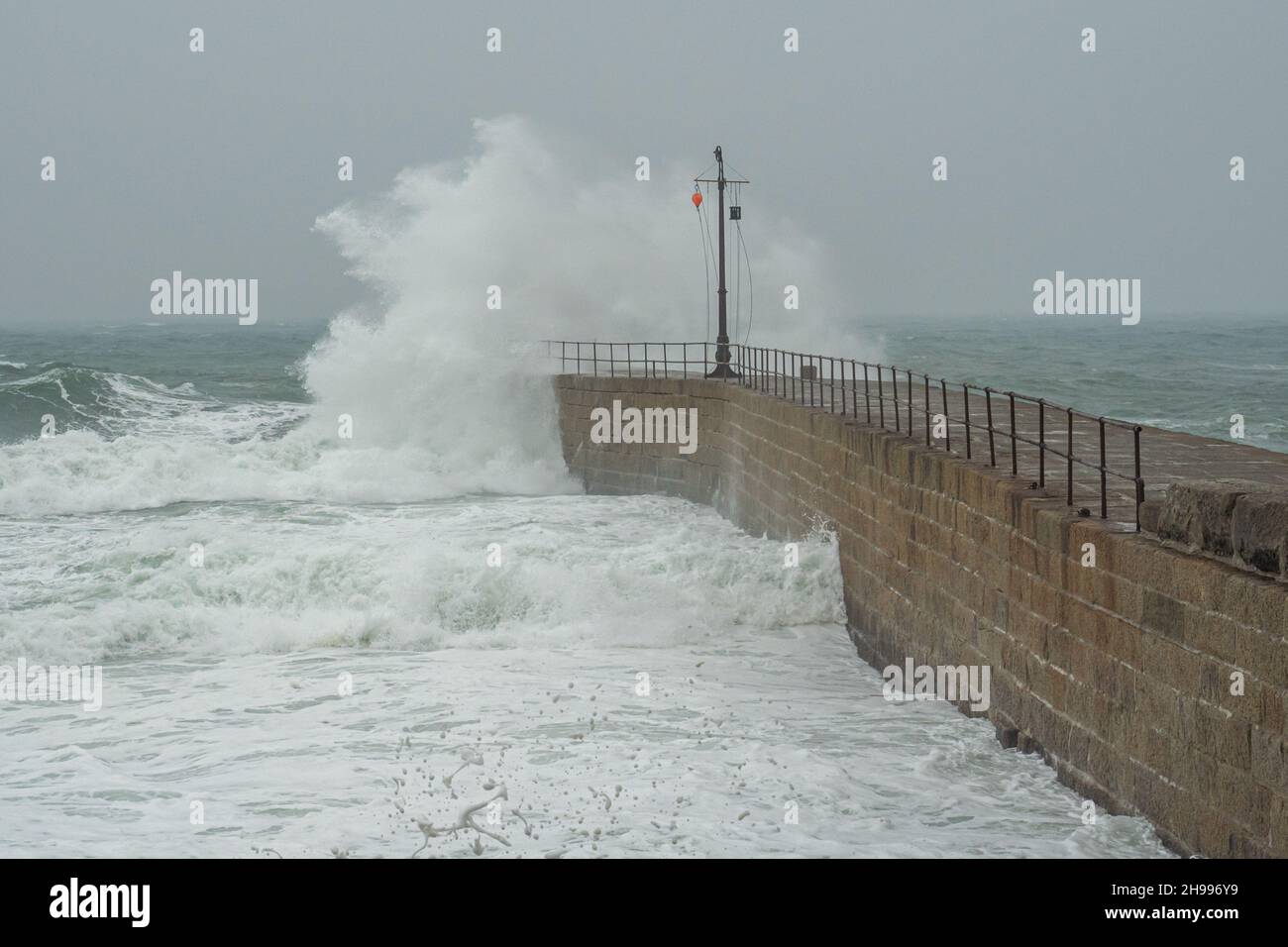 Wellenbrecher an der Meeresmauer der beliebten Stadt Porthleven in Cornwall mit ihrem malerischen Fischerhafen und der bezaubernden lokalen Landschaft Stockfoto