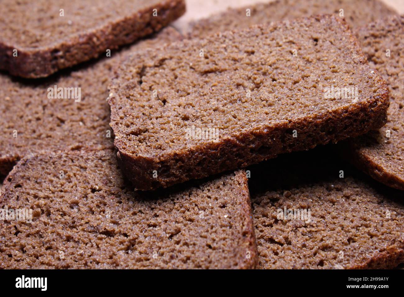 Schwarzes Brot, in Scheiben geschnitten auf einem Holzständer Stockfoto