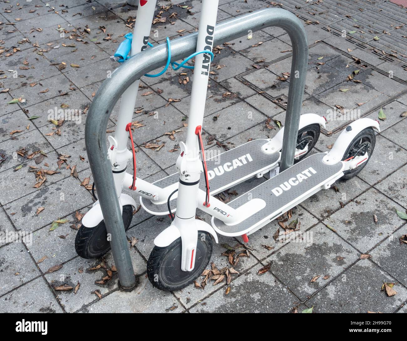 Ducati Elektro-Scooter gesperrt, um Fahrrad-Parkplatz vor dem Geschäft. Stockfoto