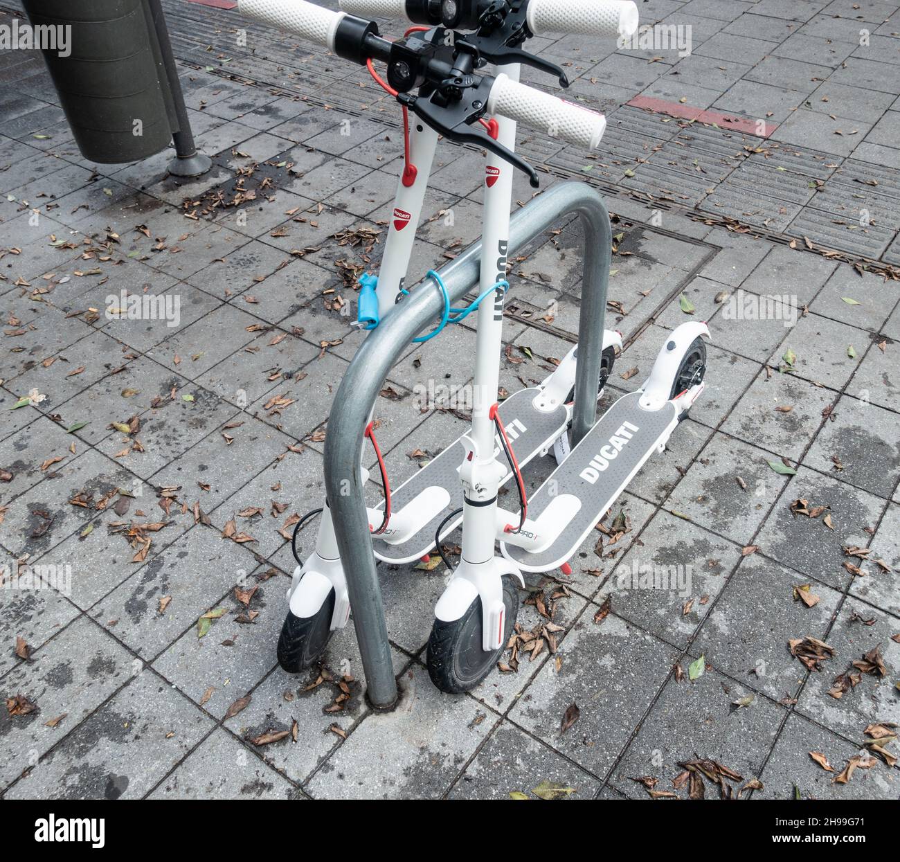 Ducati Elektro-Scooter gesperrt, um Fahrrad-Parkplatz vor dem Geschäft. Stockfoto