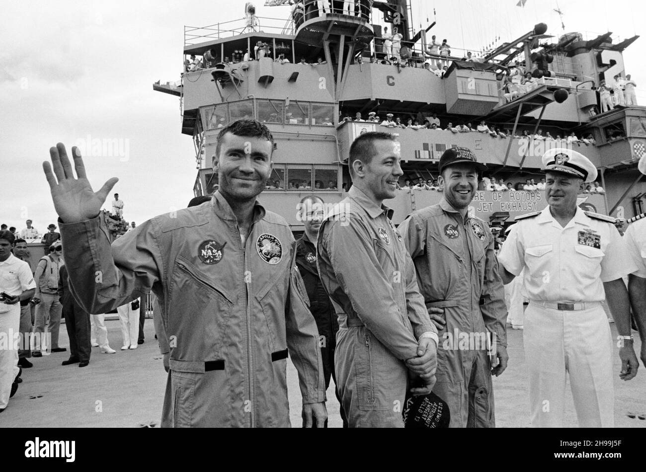Der Konteradmiral Donald C. Davis, Kommandant der Task Force 130, der Pacific Recovery Forces für die bemannten Raumfahrzeuge Missionen, begrüßt die Apollo 13 Besatzungsmitglieder an Bord der USS Iwo Jima, dem primären Rückgewinnungsschiff für die Apollo 13 Mission. Die Besatzungsmitglieder (von links), die Astronauten Fred W. Haise Jr. (winkend), Mondmodulpilot; John L. Swigert Jr., Kommandozeilenpilot; und James A. Lovell Jr., Kommandant; wurden mit dem Hubschrauber zum Schiff transportiert, nachdem sie nur etwa vier Meilen von der USS Iwo Jima entfernt einen sanften Spritzguss hinuntergefahren hatten. Spritzwasserfall um 12:07:44 Uhr (CST), Stockfoto