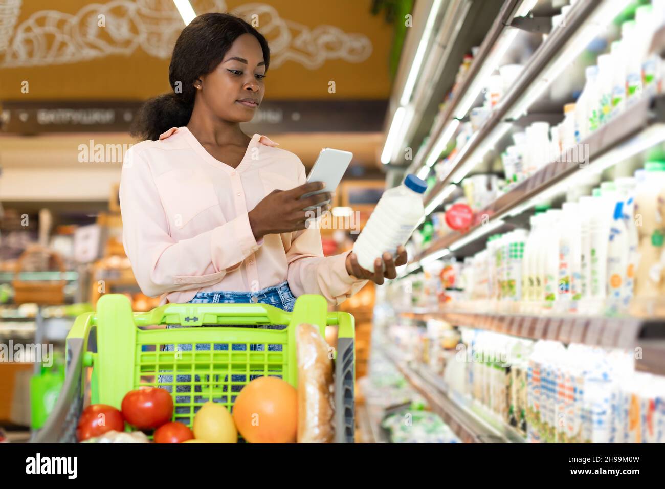 Schwarze Frau Mit Smartphone Scanning Flasche Milch Im Supermarkt Stockfoto