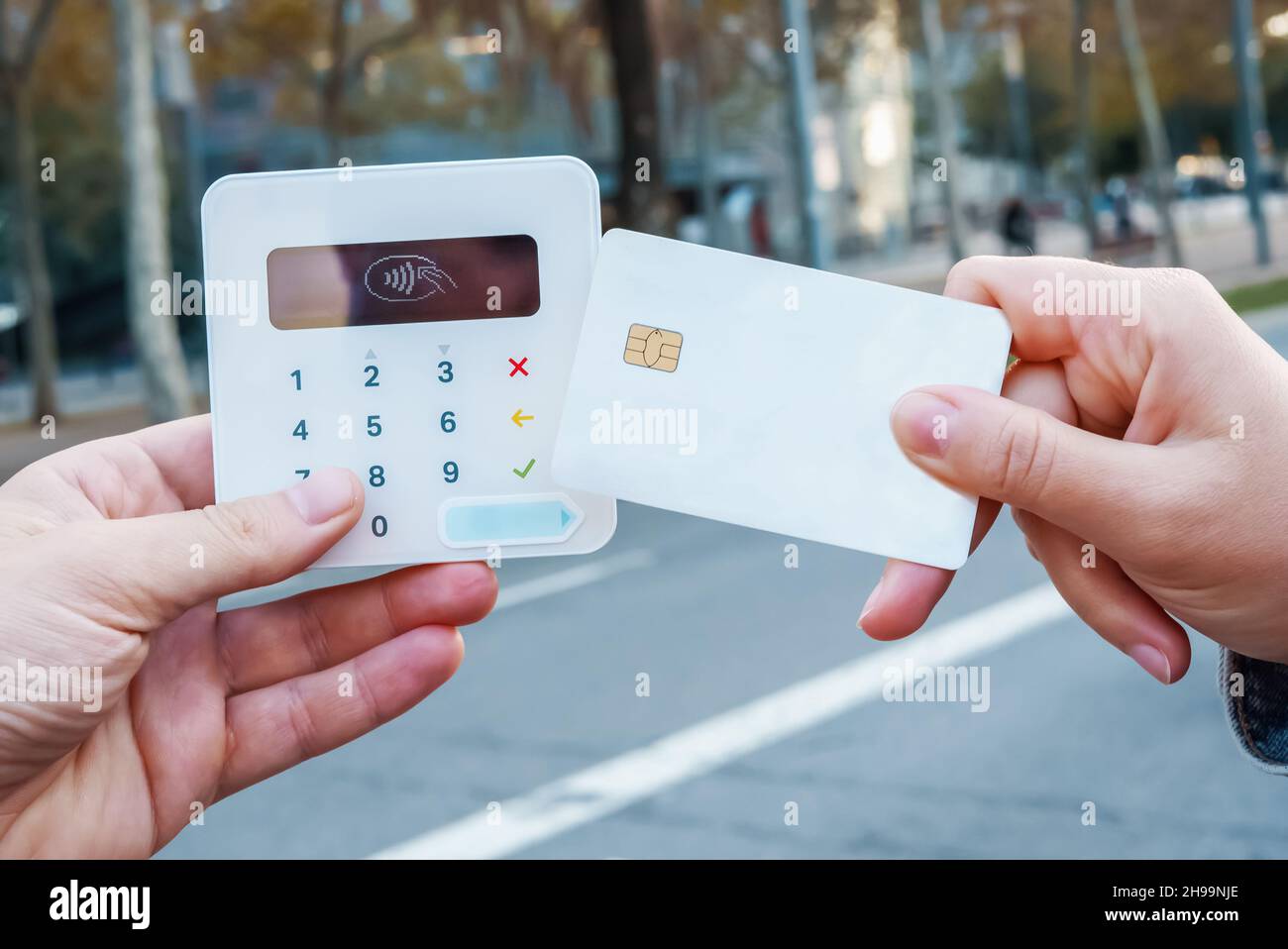 Nicht erkennbare weibliche Käuferin mit Plastikkarte beschneiden, die kontaktlosen Kauf am POS-Terminal in der Stadtstraße ermöglicht Stockfoto