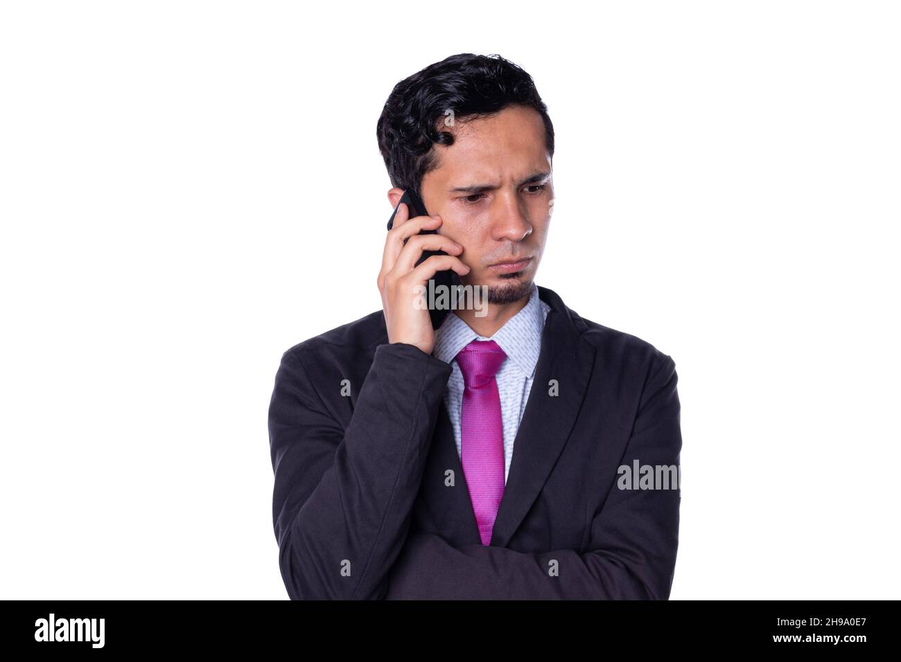 Eleganter Mann, der mit ernstem Ausdruck am Telefon spricht, isoliert auf weißem Hintergrund. Stockfoto